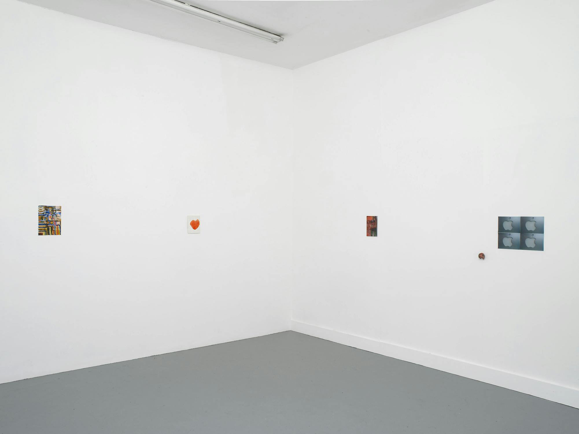 A minimalist gallery space with white walls and grey floor displays five small, colourful artworks evenly spaced on two adjacent walls; the room is mostly empty except for the artworks and a fluorescent light fitting on the ceiling.
