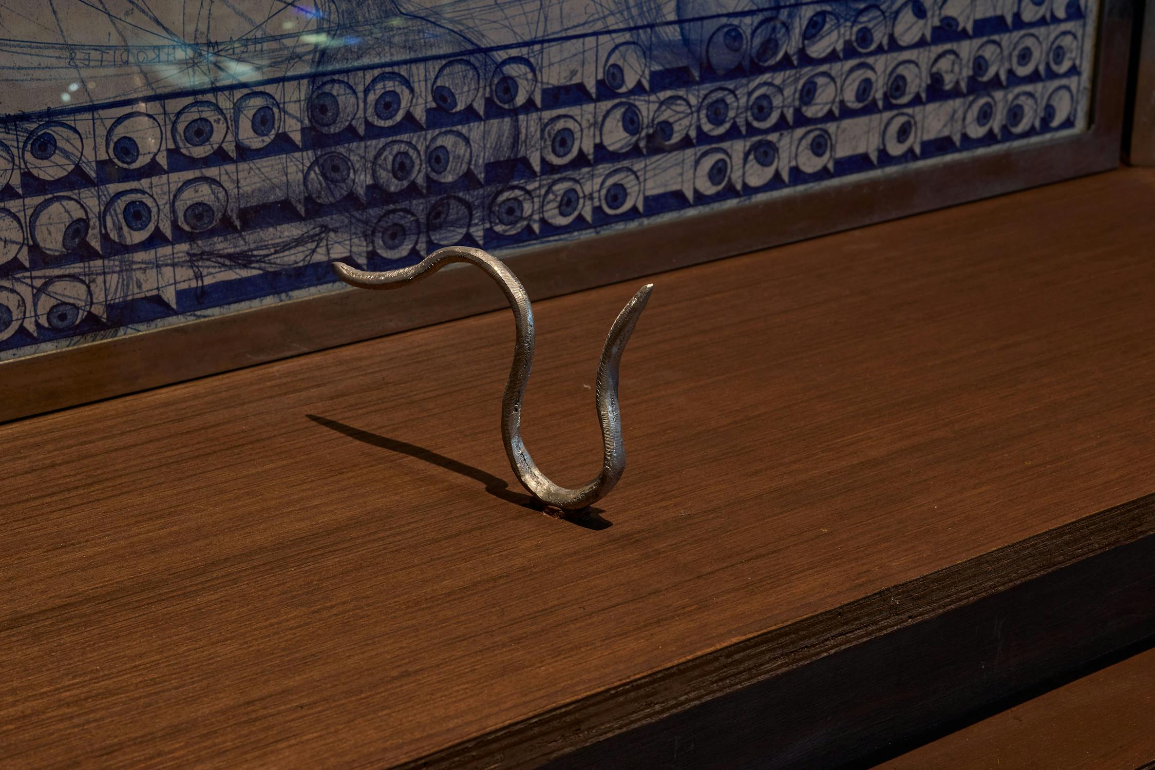 A sculpted silver worm on a wooden shelf