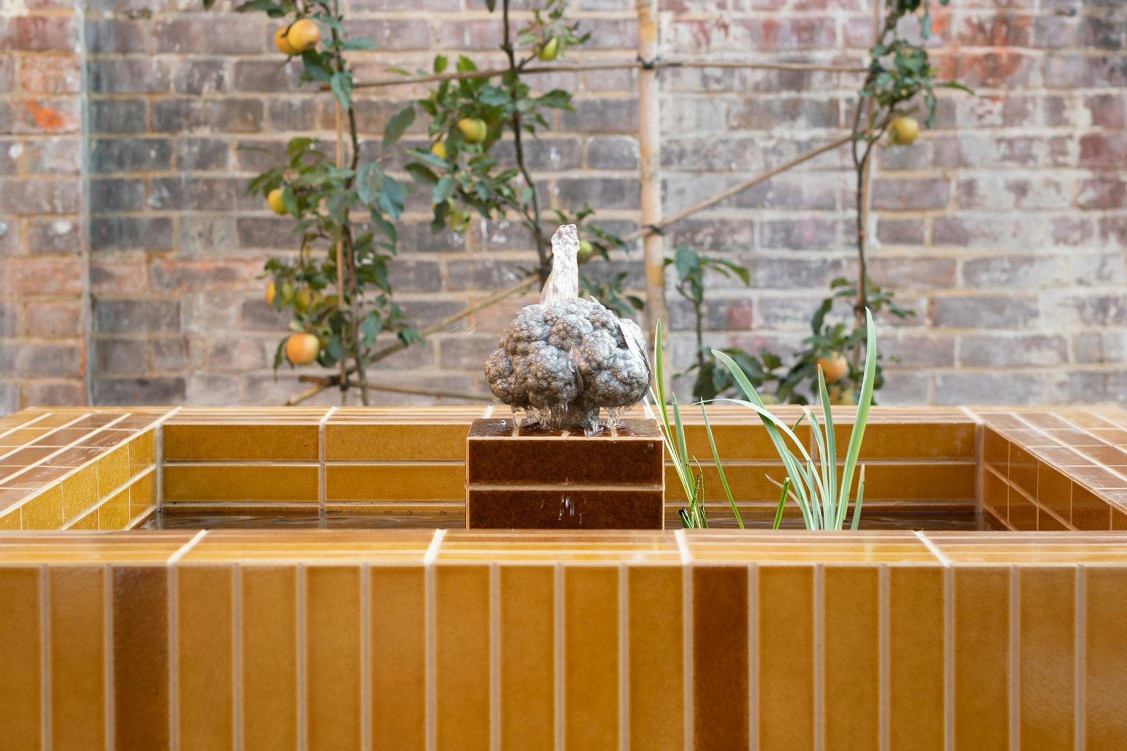 A cast-bronze cauliflower foundation set with a small square pond lined with tobacco-coloured tiles