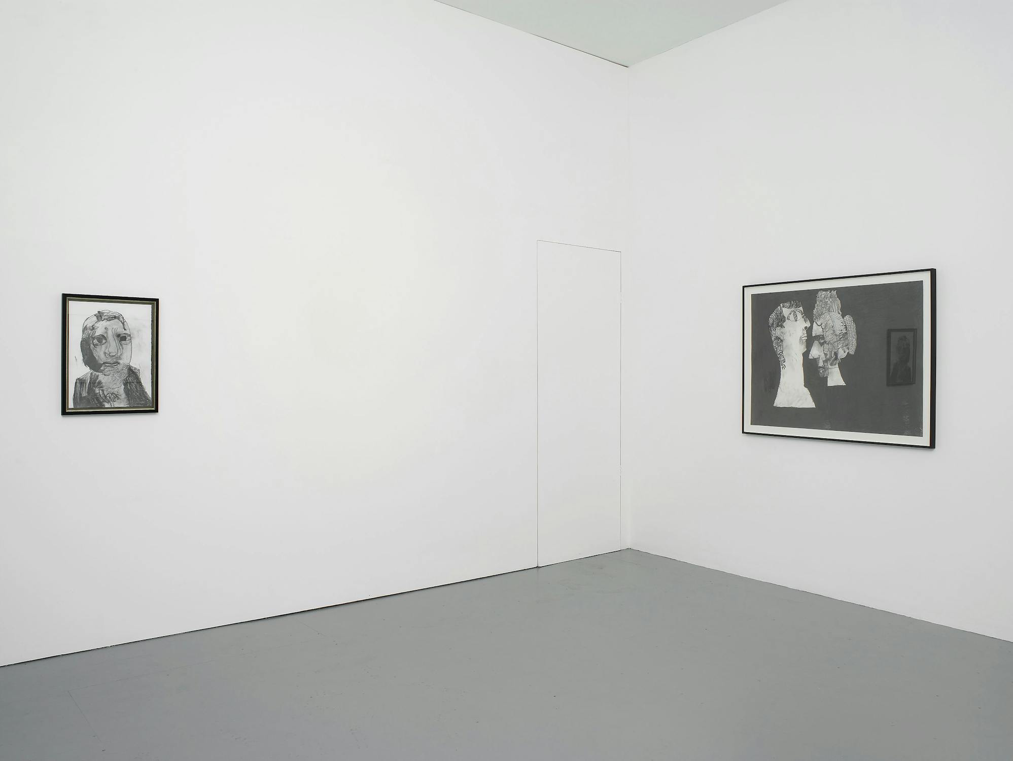 Two pencil drawings of figures with exaggerated features on white paper with black frames, hung in the corner of a white-walled gallery