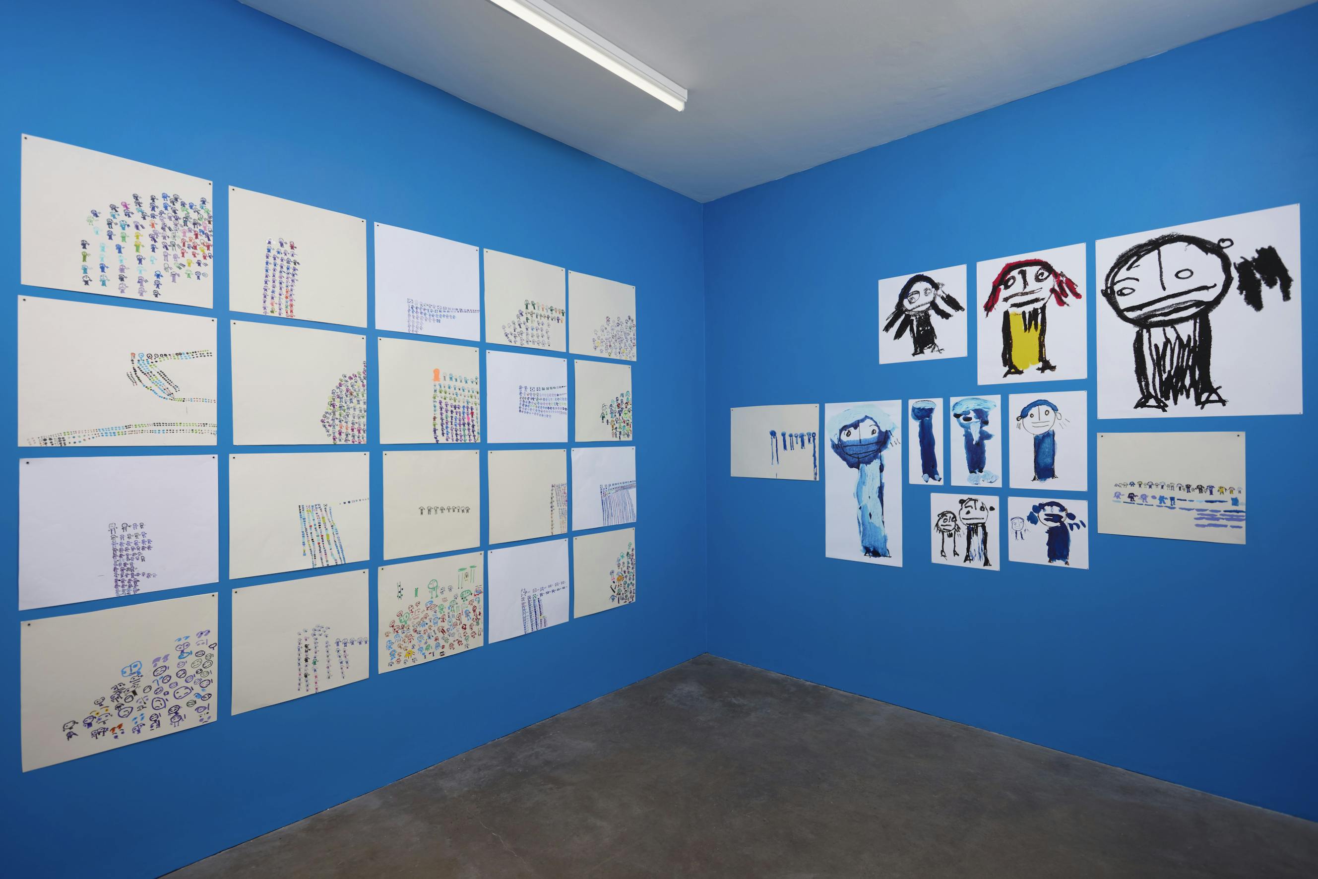 A collection of hand-drawn figures of various sizes and colours are displayed on a blue wall