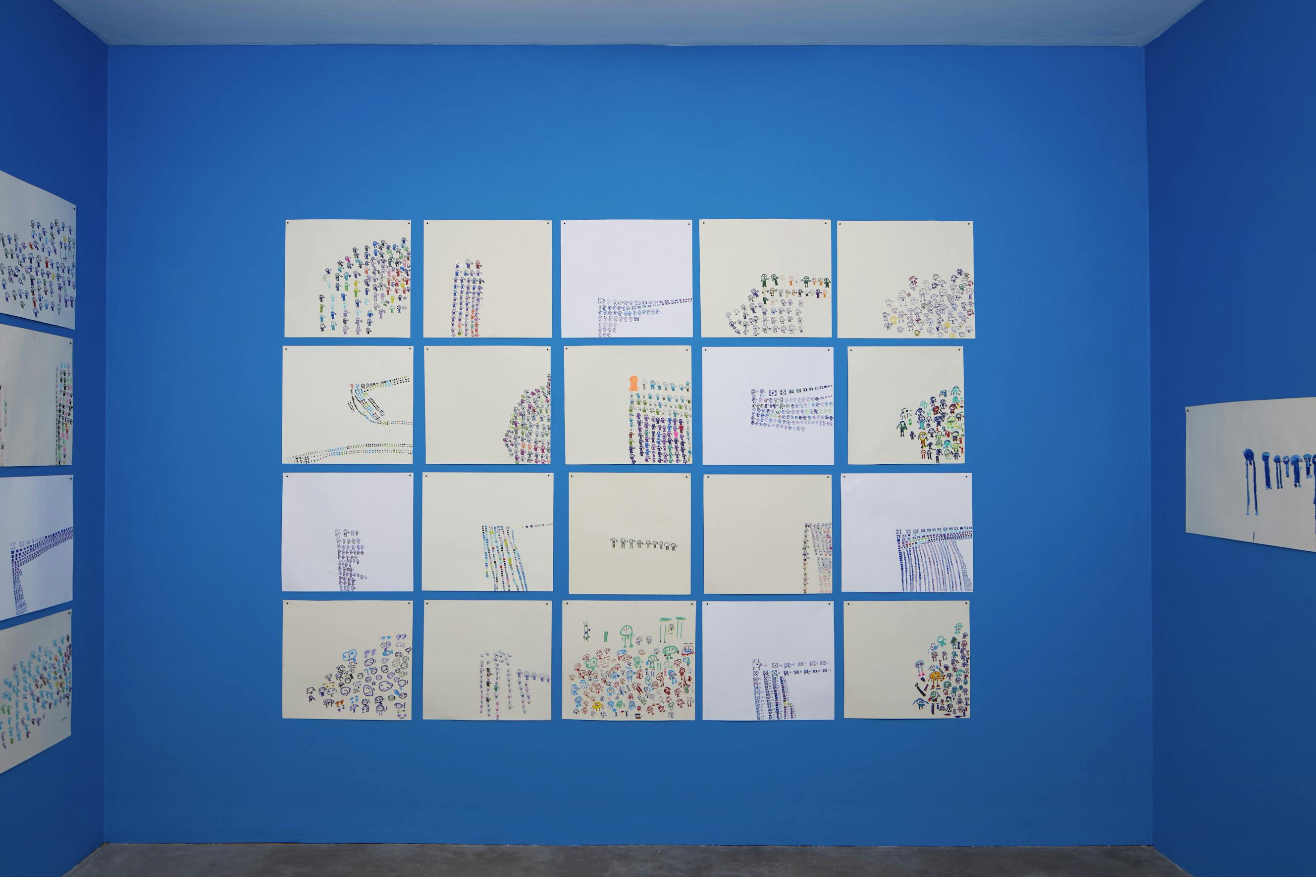 A collection of hand-drawn figures of various sizes and colours are displayed on a blue wall