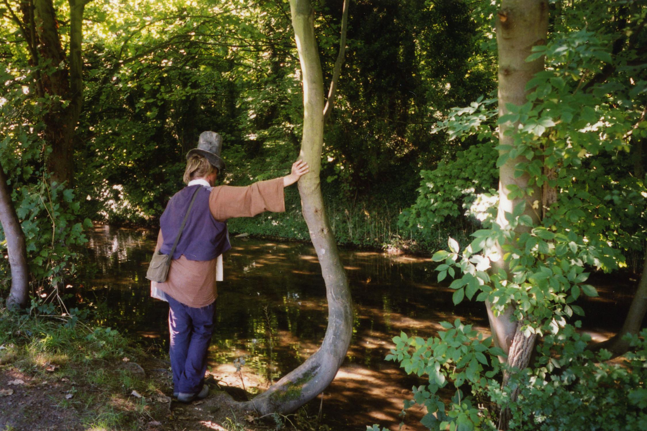 Film photograph of someone leaning on a tree looking at a river 