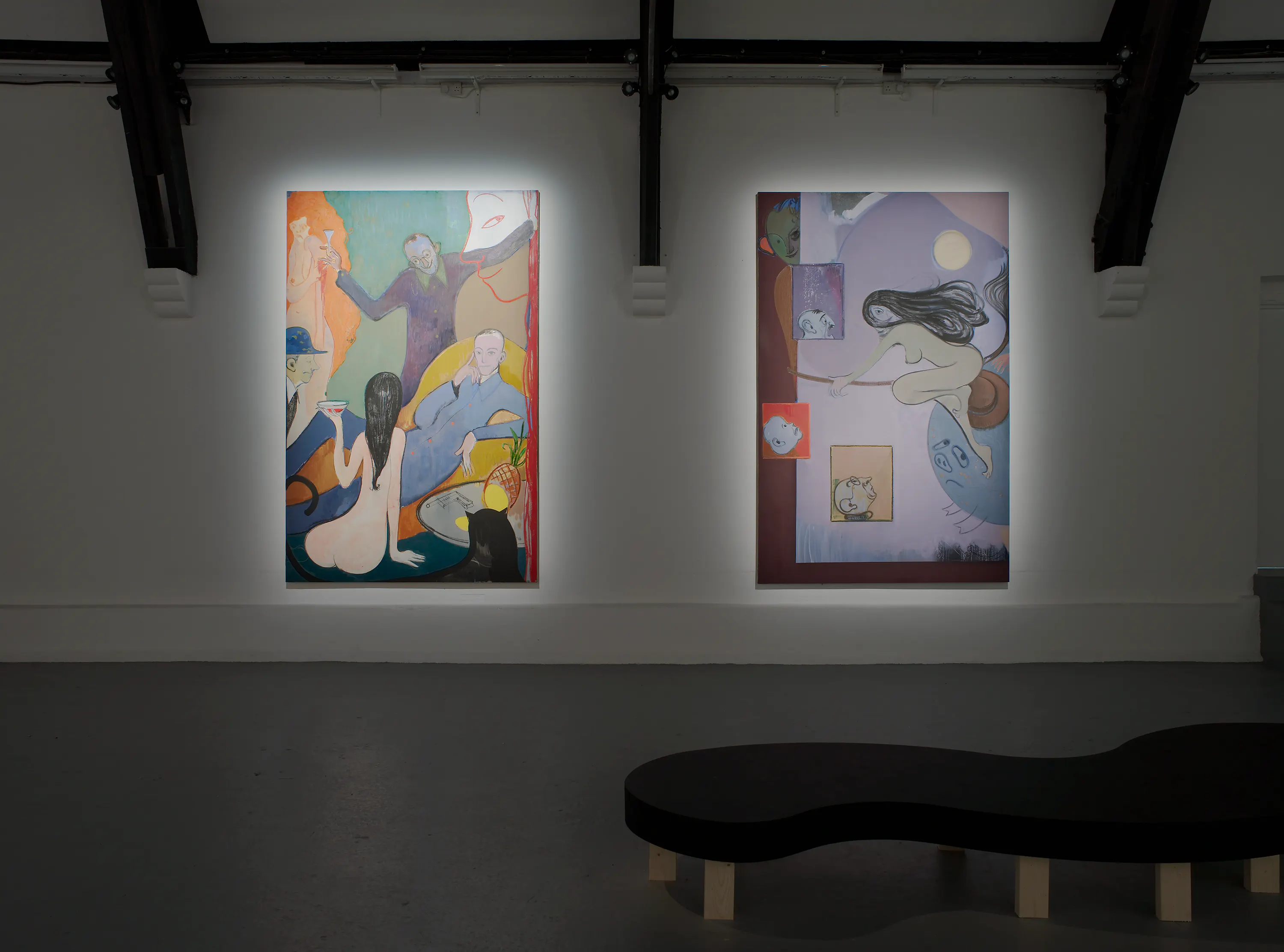 An art gallery with two illuminated abstract paintings by Sanya Kantarovksy on the wall. The left painting depicts various human figures in a surreal environment with vibrant colours. The right painting features a different abstract scene with floating figures and shapes. A minimalist black bench is in the foreground.