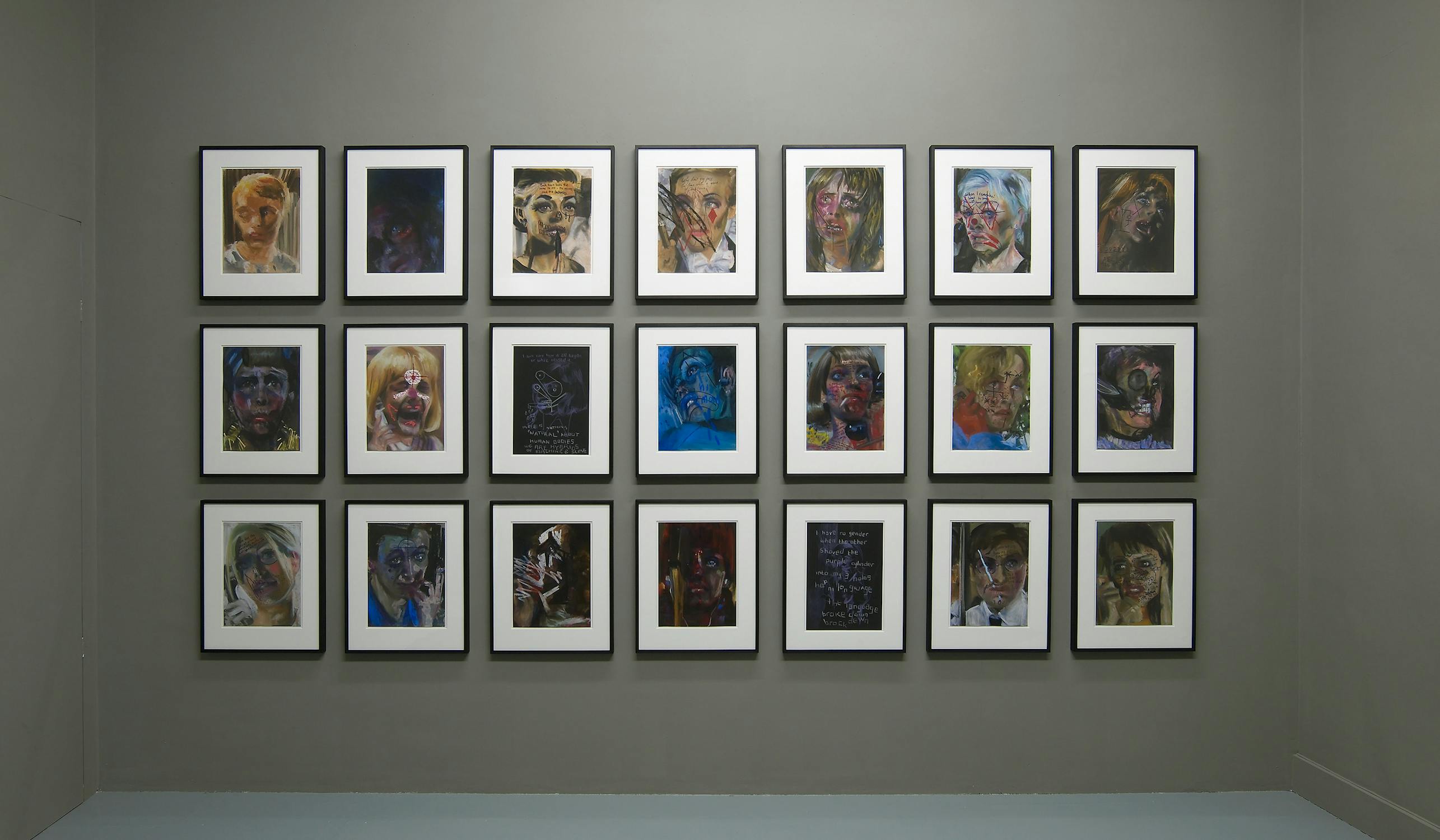 A gallery wall displaying a grid of twenty-four framed artworks. The pieces feature expressive portraits with vivid, bold colors and dark backgrounds. The arrangement is symmetrical, and each frame is evenly spaced on the wall.