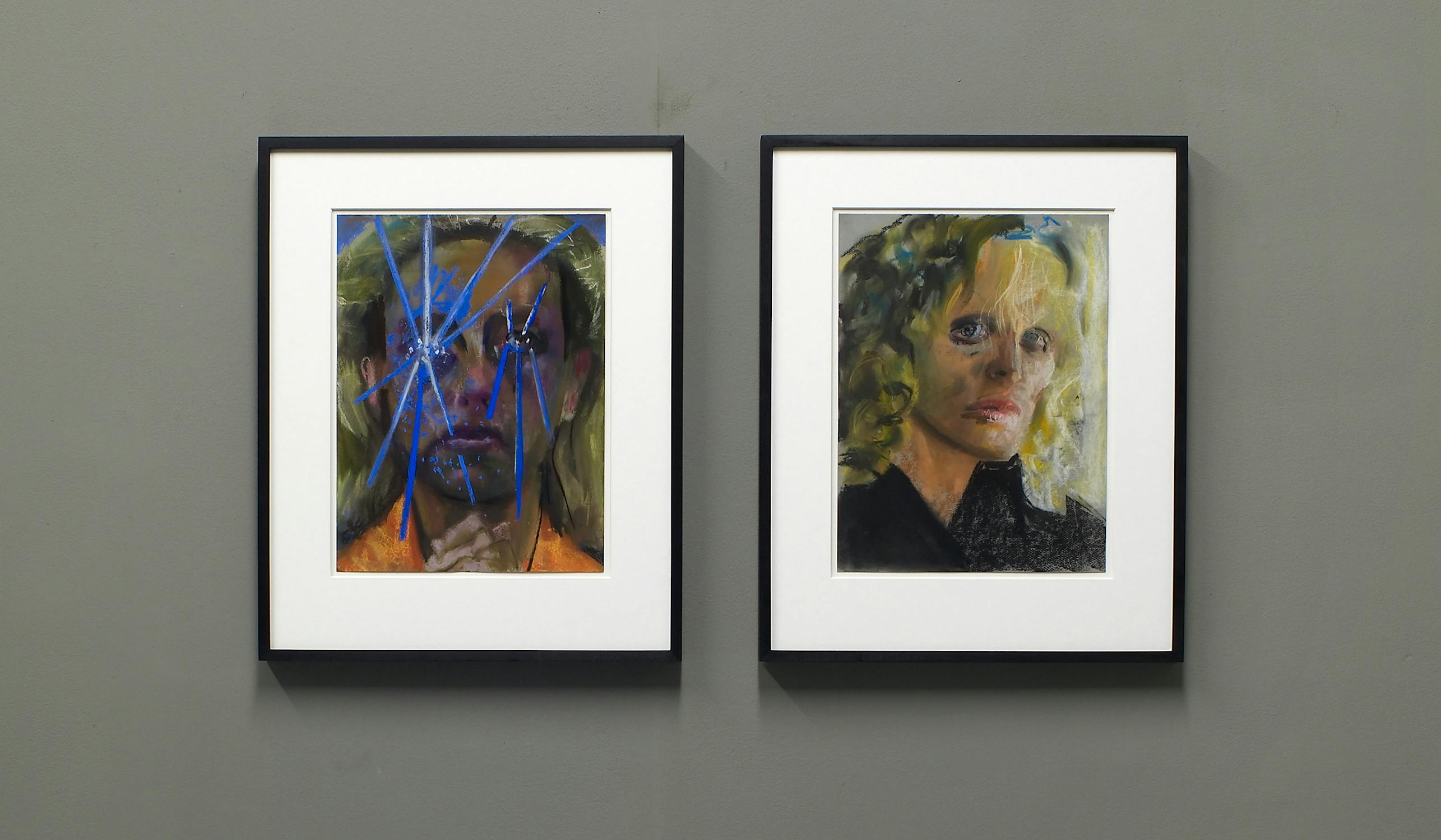 Two framed abstract portraits on a gray wall. The left image features a face with blue streaks and shadowed details. The right image shows a person with blond hair and subtle facial features. Both have expressive, painterly styles.