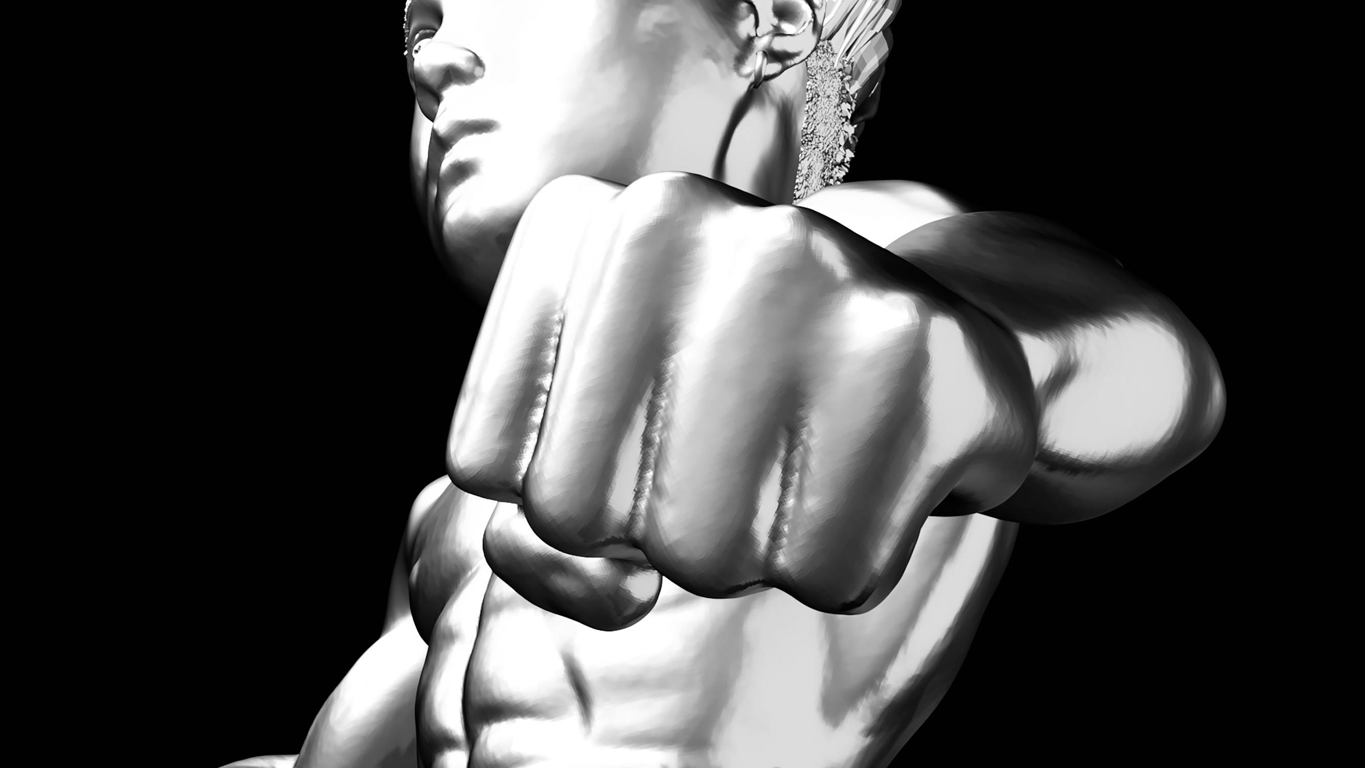 A close-up black and white image of a metallic sculpture depicting a muscular, shirtless man striking a powerful fist-forward pose. The sculpture highlights detailed anatomy and dynamic movement, set against a black background.