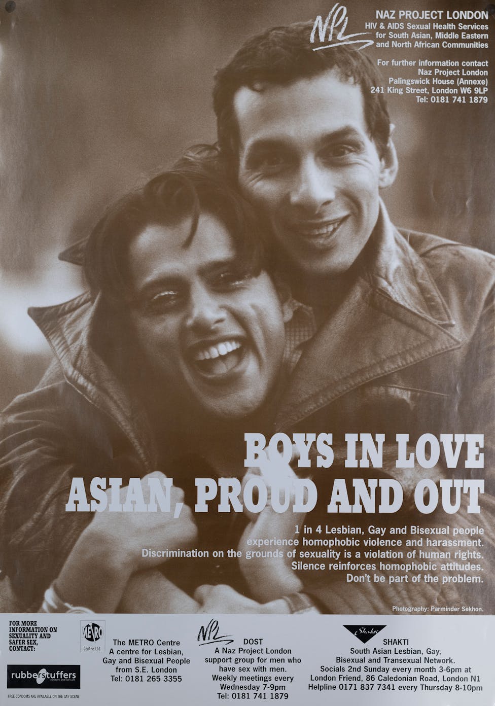 A smiling couple embraces outdoors. The poster reads: “BOYS IN LOVE: ASIAN, PROUD AND OUT.” It promotes support for Asian LGBTQ+ individuals and lists help center contacts in London.