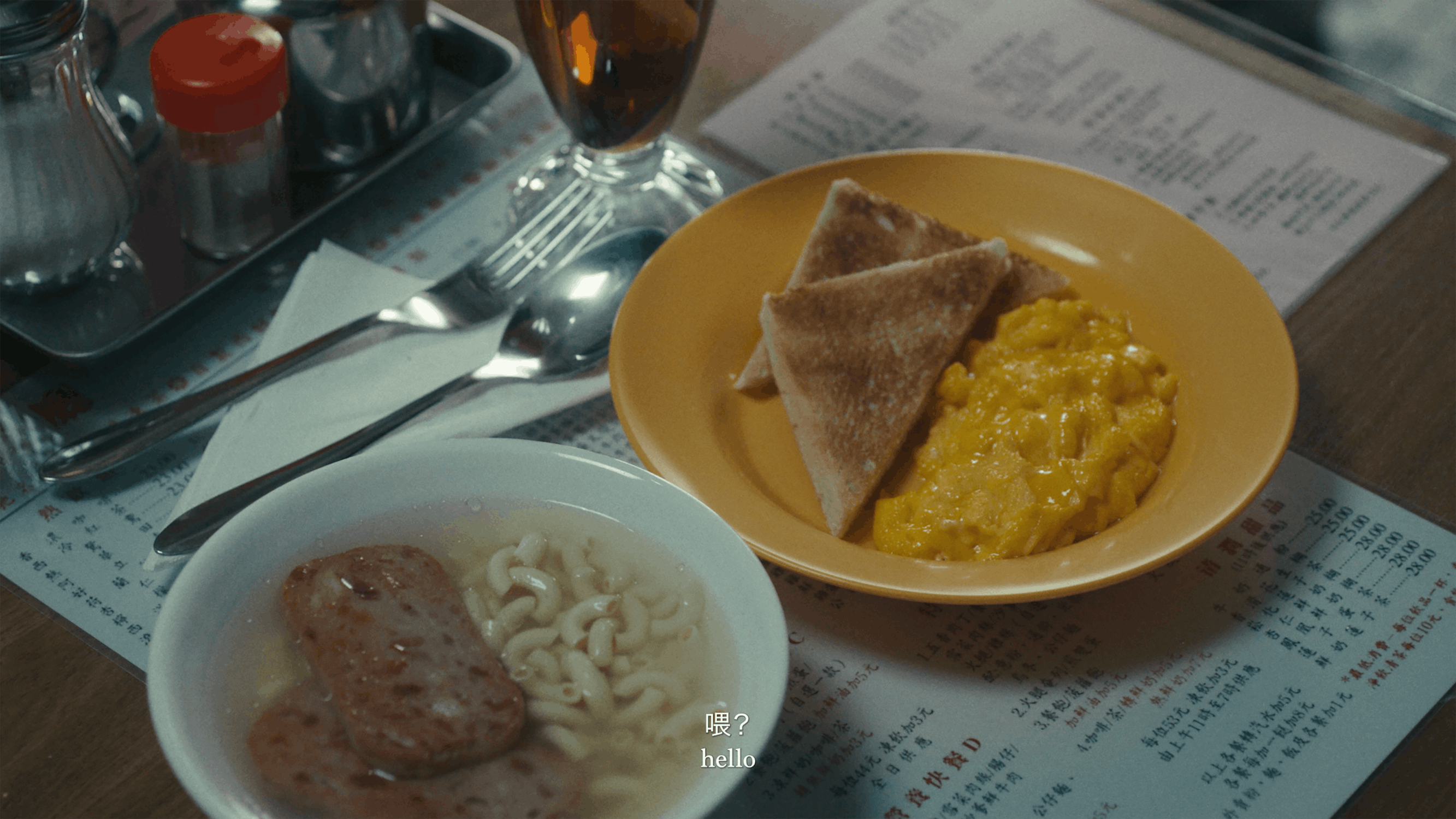 A table with a bowl of instant noodles and luncheon meat, a plate of scrambled eggs and toast, a glass of iced tea, and condiments. A menu is underneath, and subtitles read "hello.