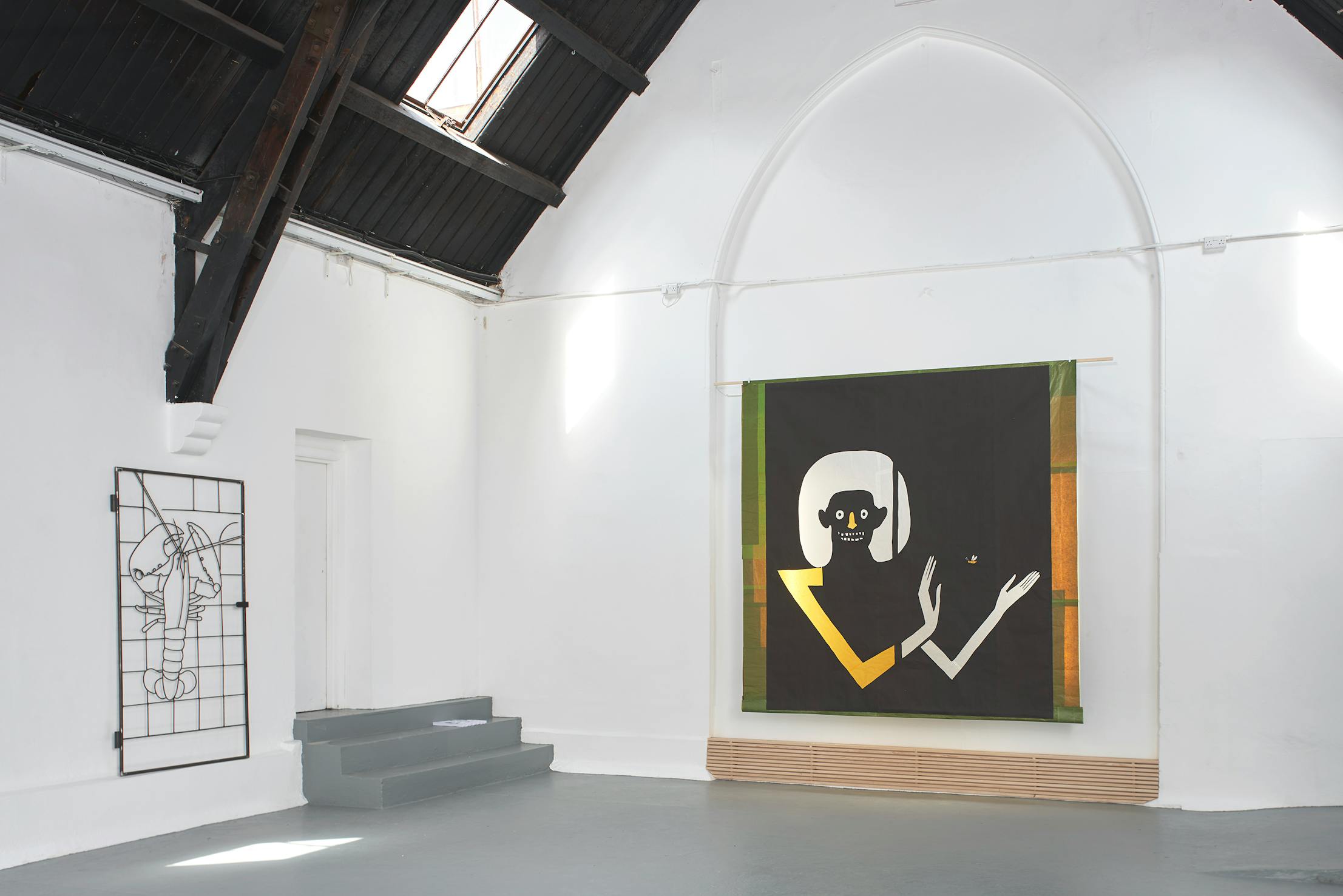 A bright white gallery with high dark rafters displays two artworks: a large, abstract painting of a seated figure with geometric shapes and muted colours, and a minimalist wire sculpture on the left wall resembling a stylised portrait. Grey steps lead to a small door.