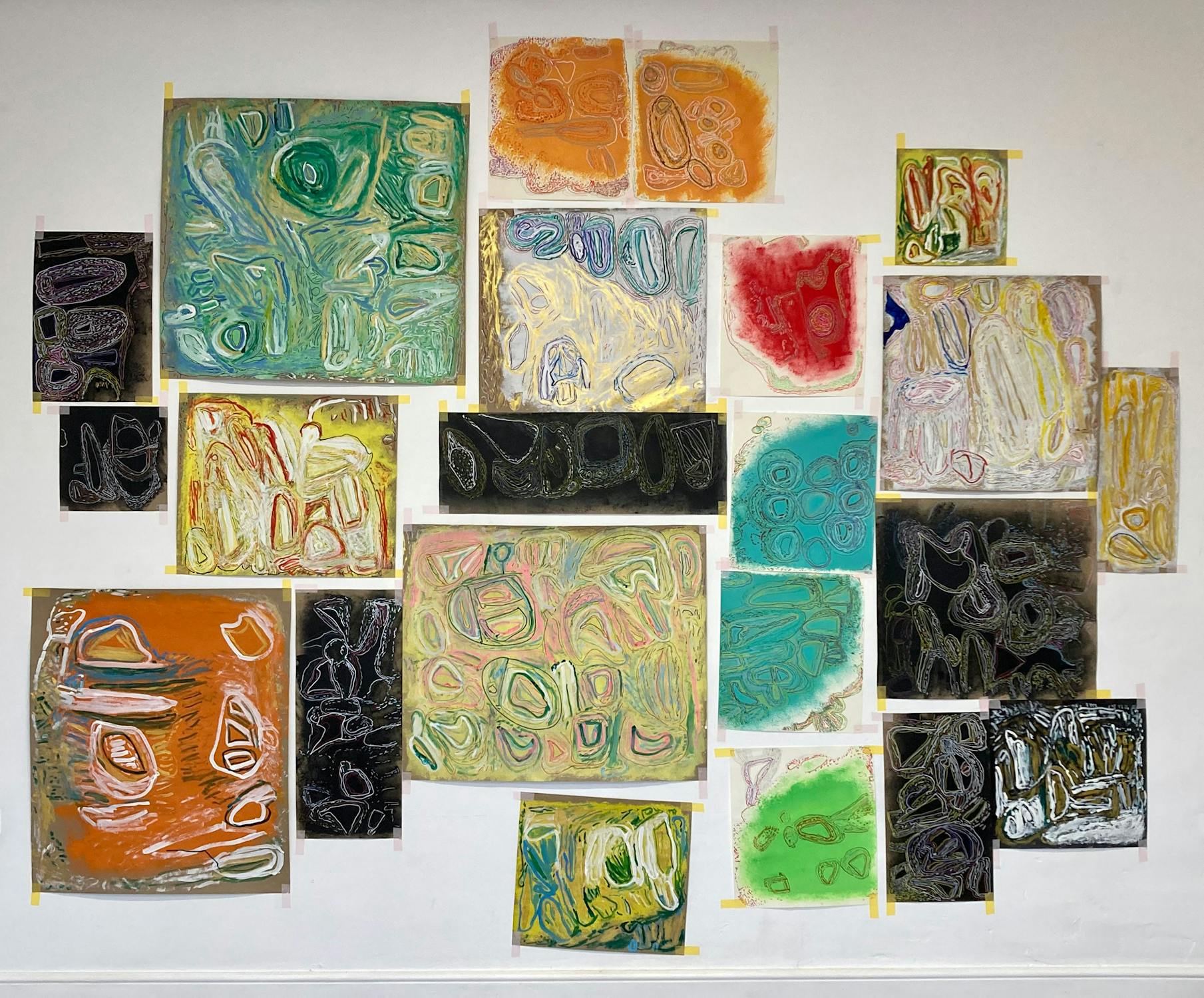 A wall filled with an eclectic mix of abstract paintings, each featuring intricate, swirling patterns and vibrant colors like orange, green, blue, and red. The artworks are arranged in a mosaic-like fashion.