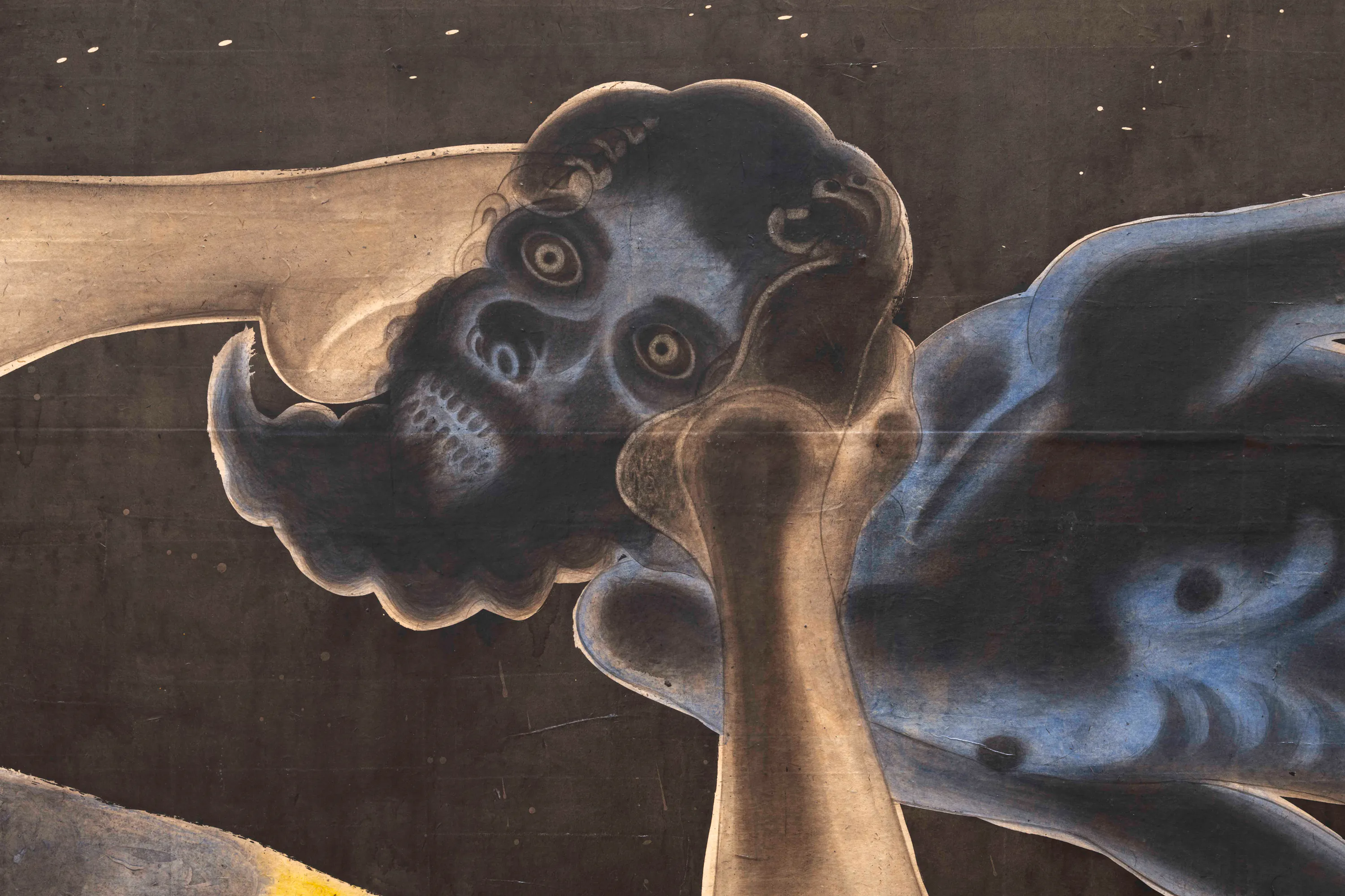 An illustration of a shadowy figure holding a man's head with their toes. The background is dark with scattered white dots, resembling stars. The figure is rendered in dark blues and blacks with lighter skin tones for the skull and one of its hands.