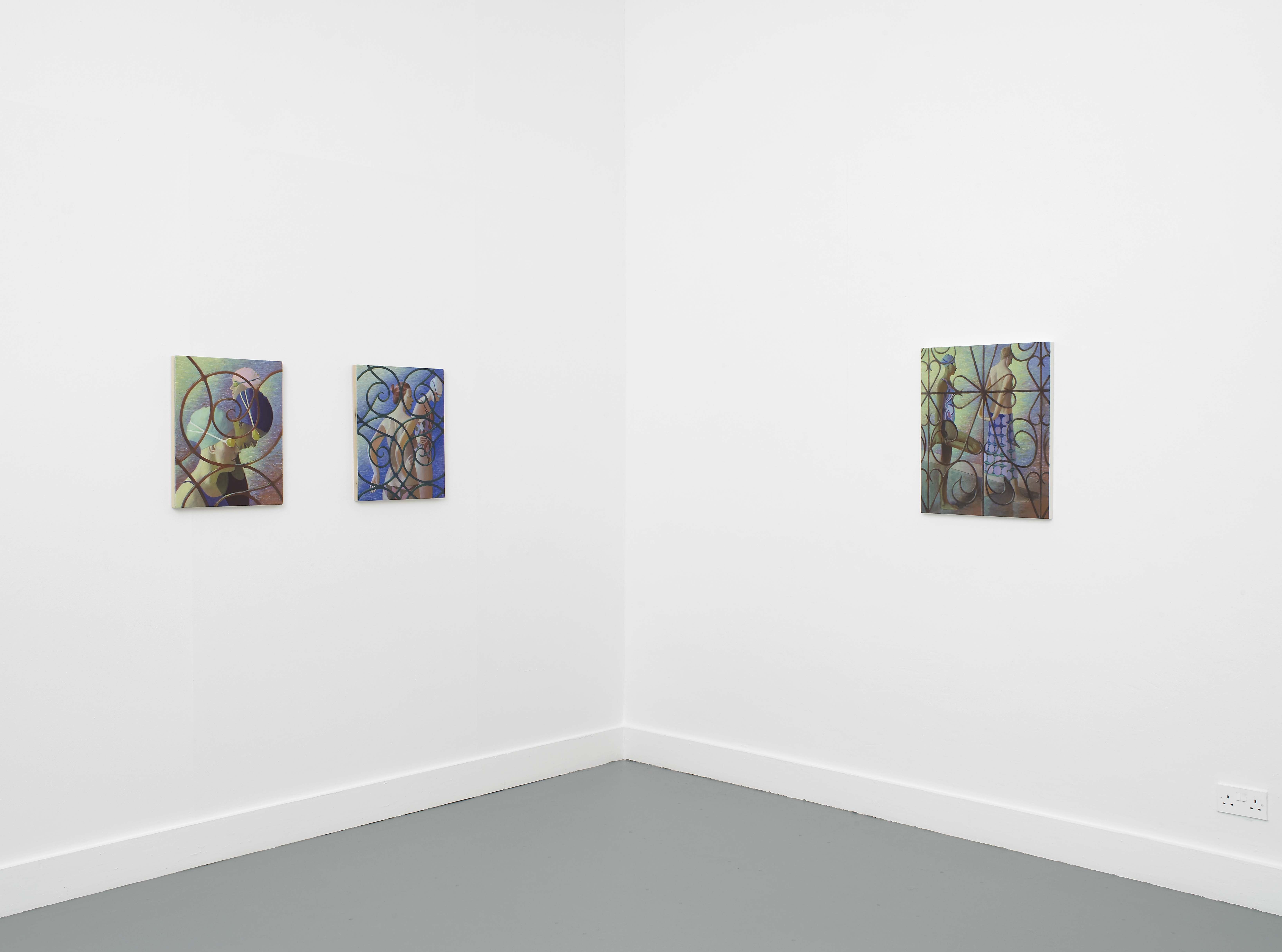 Three colourful paintings by Benjamin Senior with looping circular patterns hang on the white walls of a minimalist gallery corner. Two are on the left wall, spaced evenly, and one larger piece is on the right wall. The floor is grey, and the space is empty.
