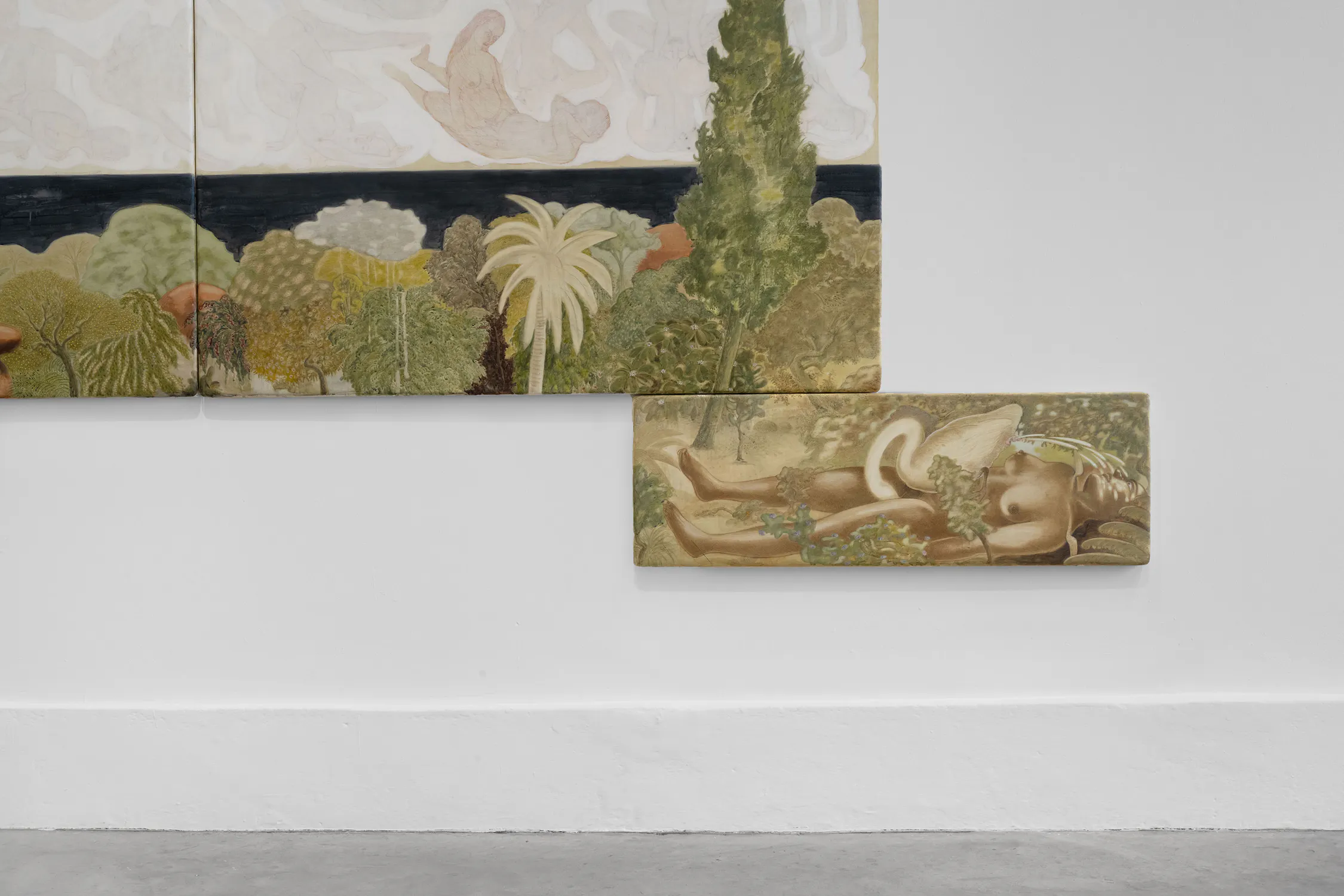 Two landscape paintings hang on a white wall. The larger painting shows abstract trees, plants, and a dark horizontal strip suggesting water or sky. The smaller painting below depicts a reclining nude figure partly covered by foliage, blending into the lush scenery.