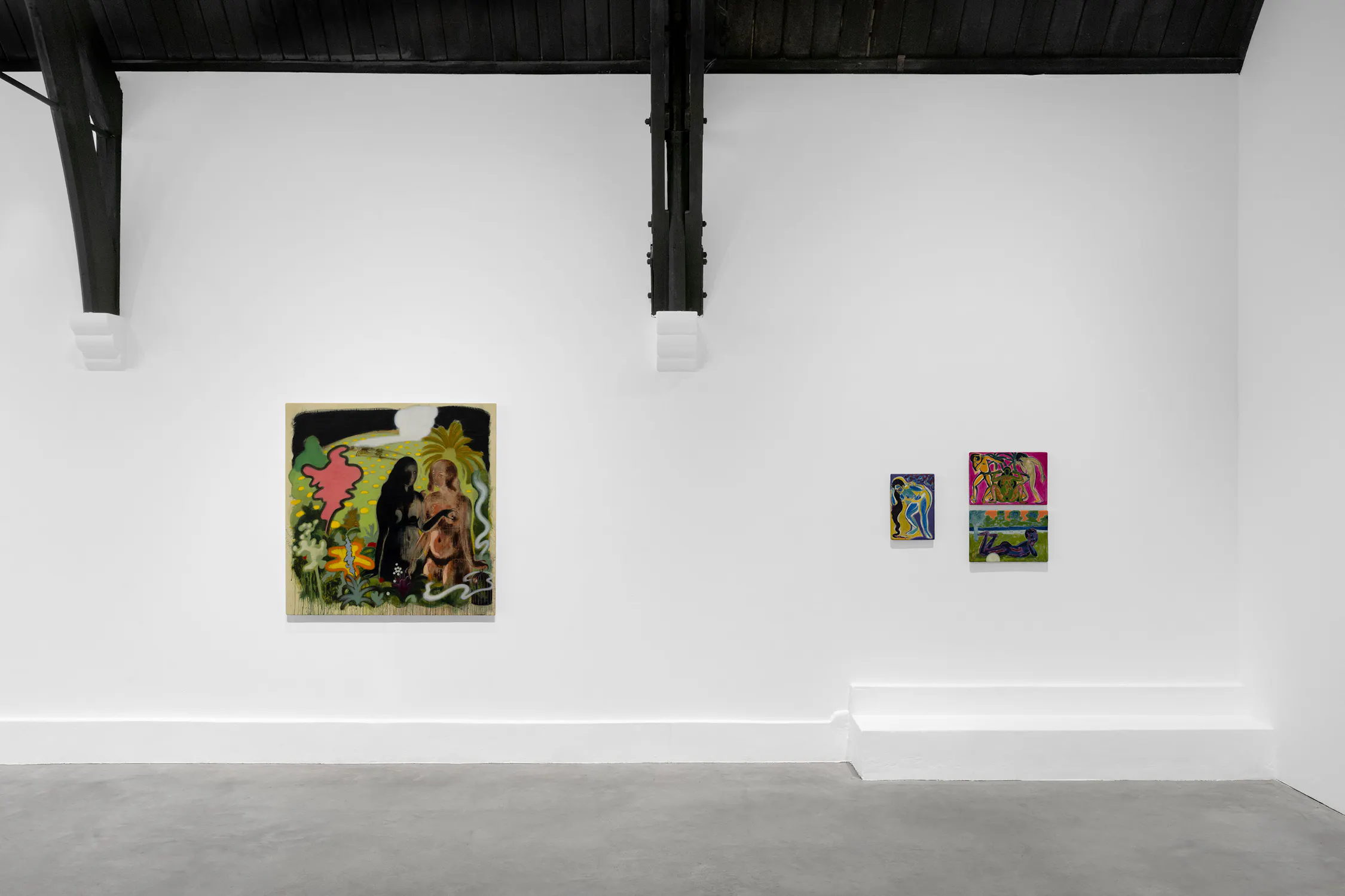 A white-walled art gallery displays four colourful paintings. On the left is a large painting featuring two figures, one dark and one light, surrounded by tropical plants. To the right, three smaller abstract paintings hang side by side on the white wall.