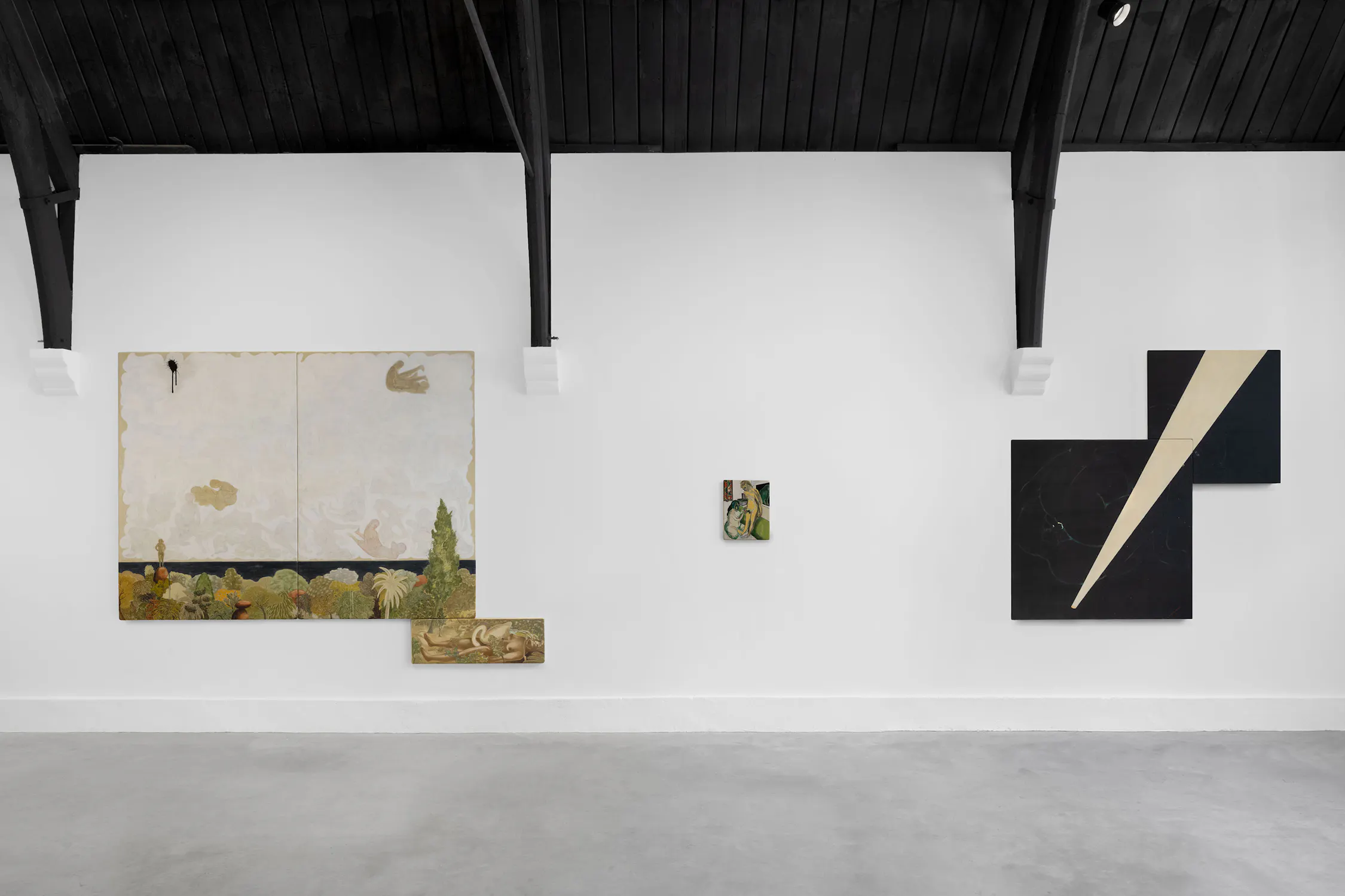 A white gallery wall displays three artworks: a large painting with a natural scene and gold tones on the left, a small portrait in the centre, and a geometric black painting with a sharp white diagonal stripe on the right. The ceiling is dark wood with exposed beams.