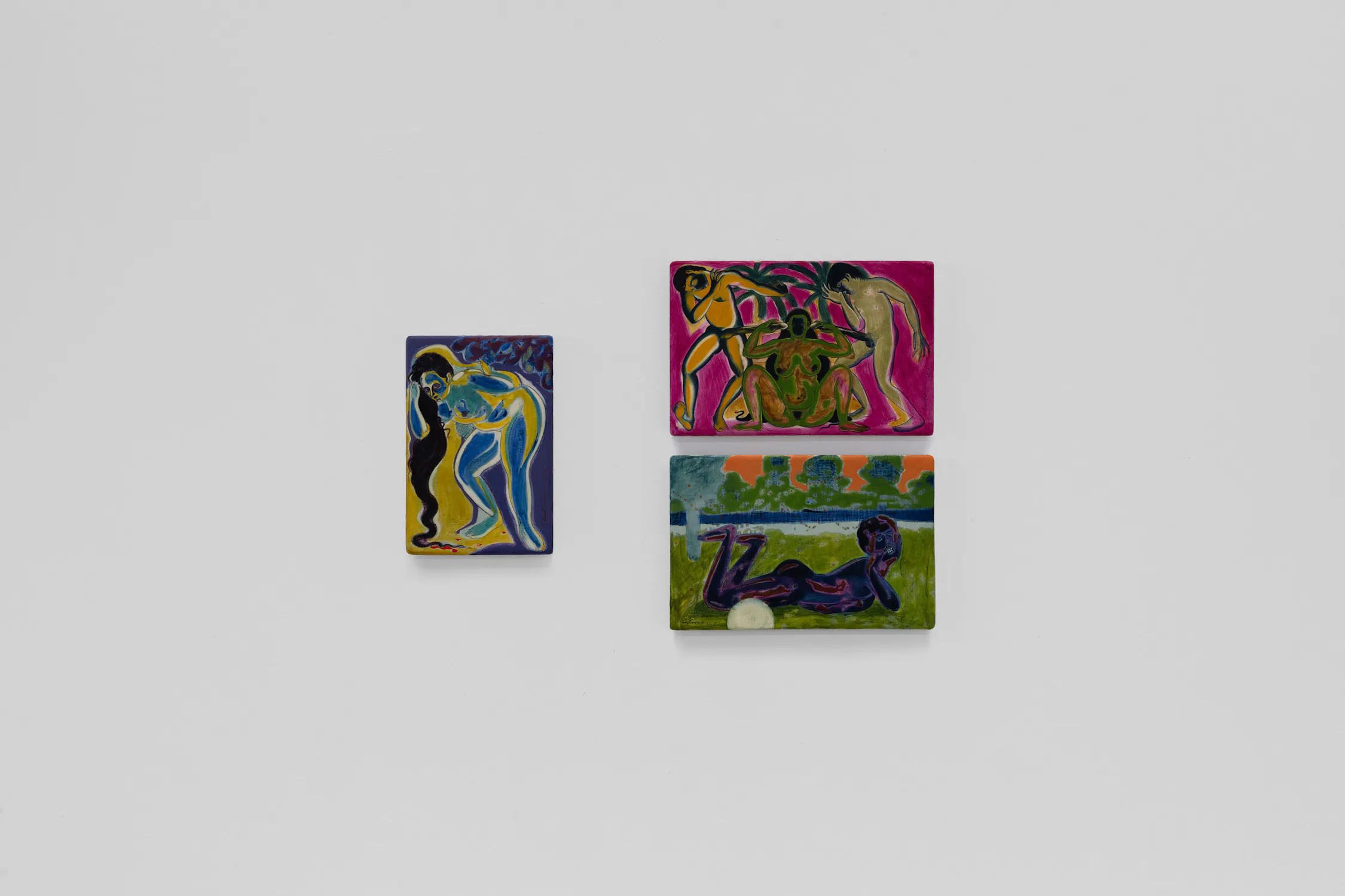 Three colourful, small rectangular paintings hang on a plain white wall. Each artwork depicts abstract human figures in vivid blues, greens, and purples, set against expressive backgrounds with flowing lines and dynamic forms.