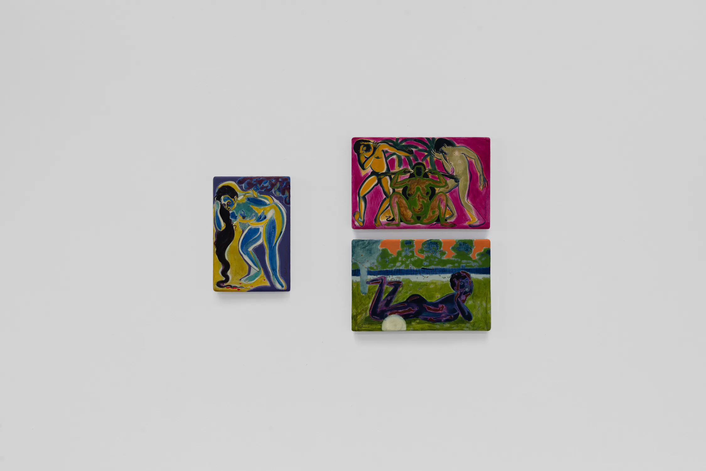 Three colourful, small rectangular paintings hang on a plain white wall. Each artwork depicts abstract human figures in vivid blues, greens, and purples, set against expressive backgrounds with flowing lines and dynamic forms.