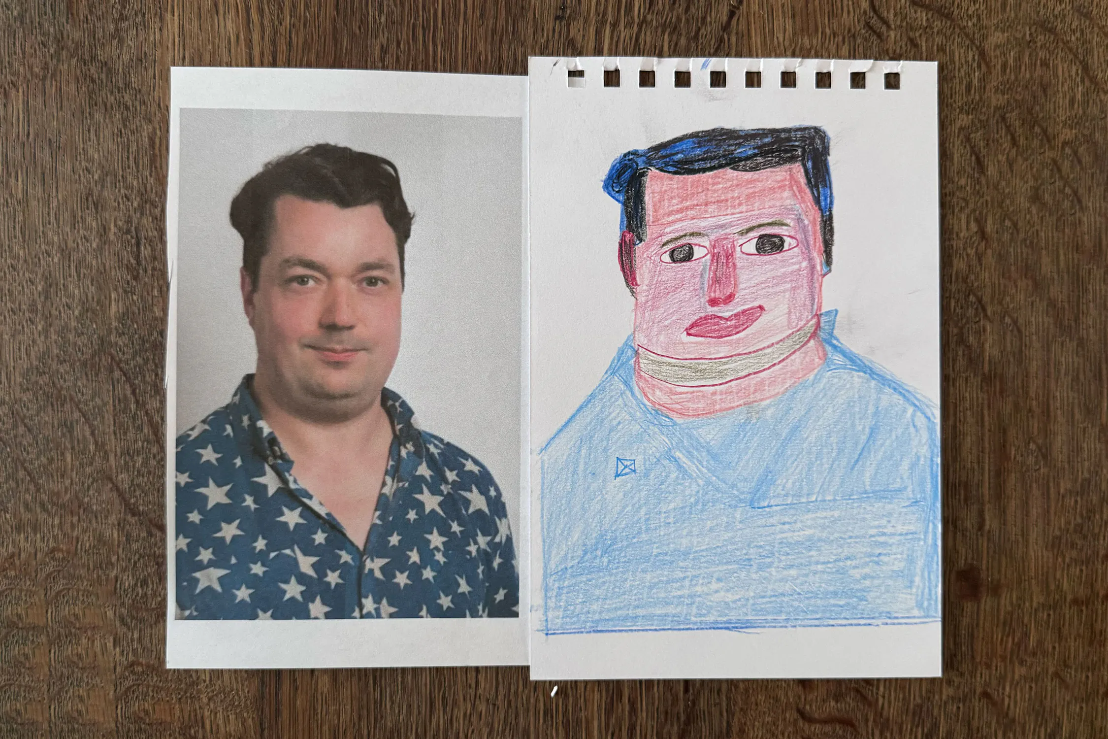 A printed colour photo of Studio Voltaire director Joe Scoltand is placed beside Christine Hazell's colourful drawing of a similar face on white paper. The drawing mimics the photo’s features with exaggerated shapes, bold lines, both on a wooden surface.