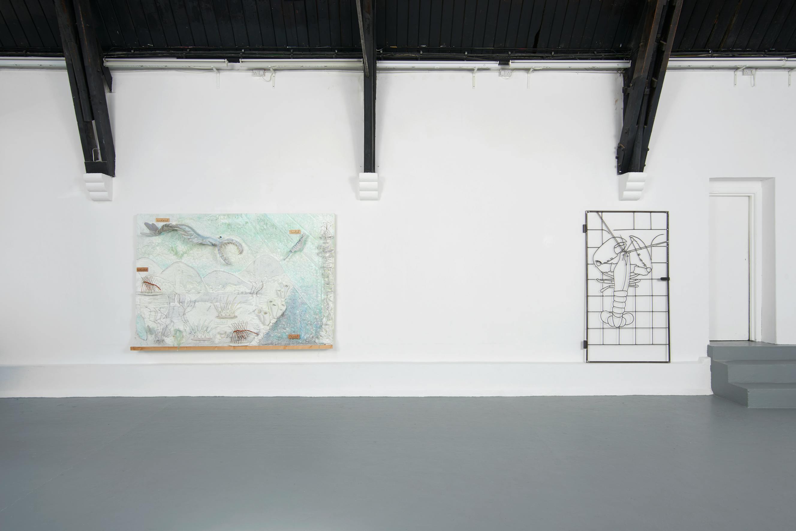 A minimalist art gallery with white walls and grey floors. On the left, a large abstract painting with soft pastel colours hangs. To the right, a black metal grid sculpture is mounted on the wall. Exposed ceiling beams are visible at the top.