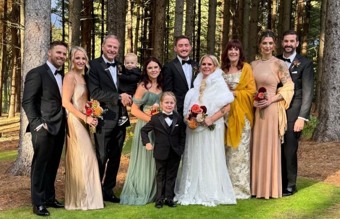 Intimate wedding moment with bride and groom surrounded by guests in formal black-tie attire.