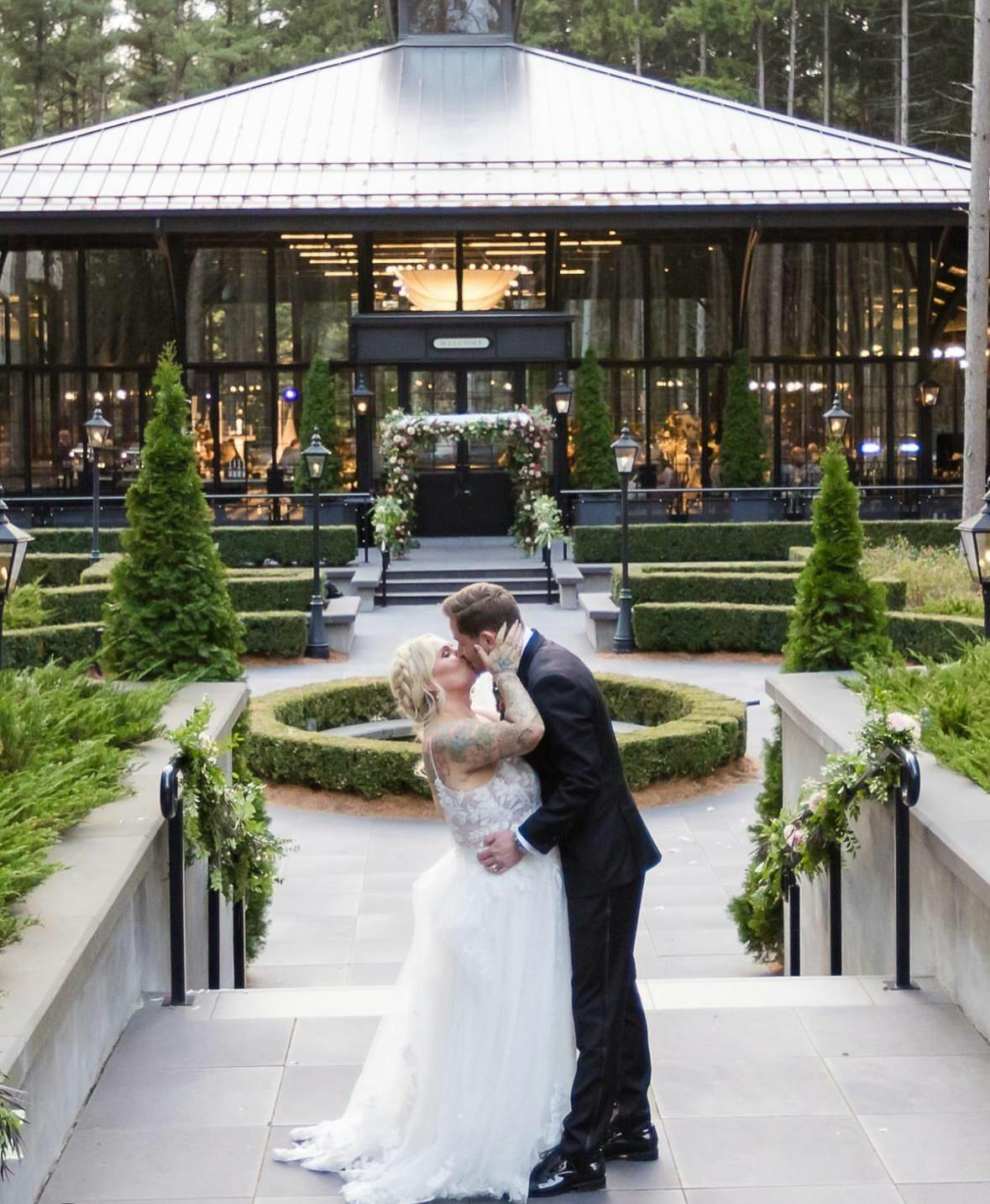 Newlywed couple kissing in an intimate moment outdoors at their wedding venue.