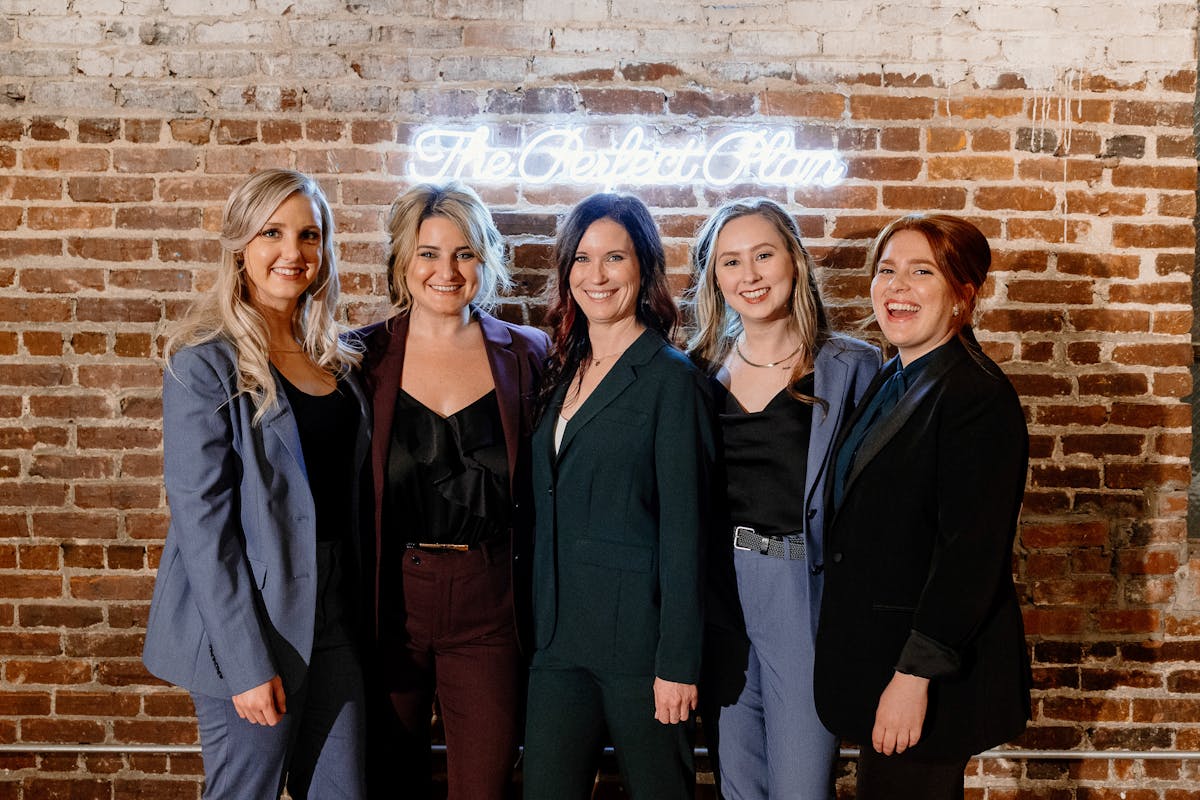 Women's business team in matching women's suits in different colors including light blue suits, burgundy suits, and a black tuxedo for women at a work expo outfits.