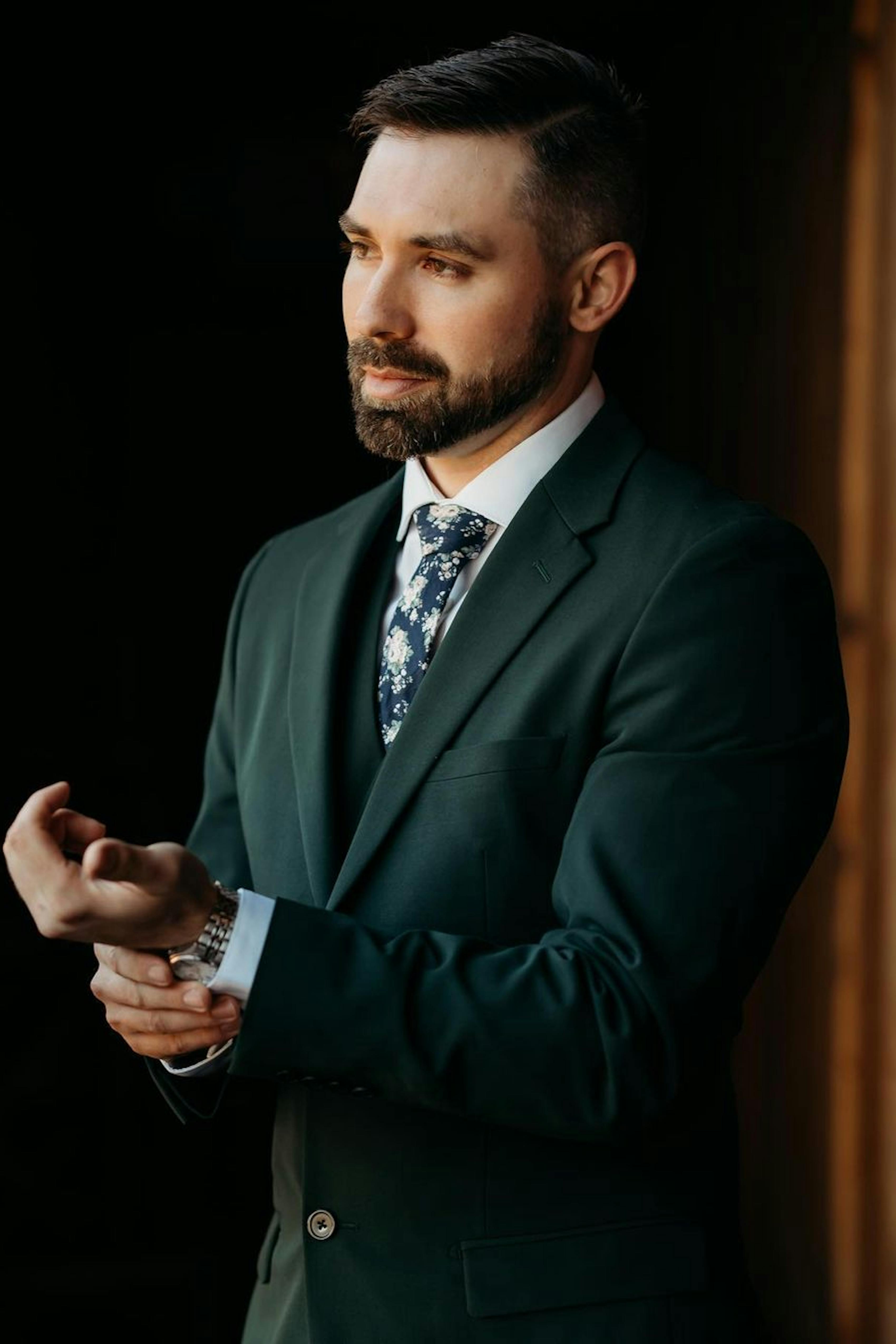 Forest green suit and green suit vest with floral neck tie for groomsmen.