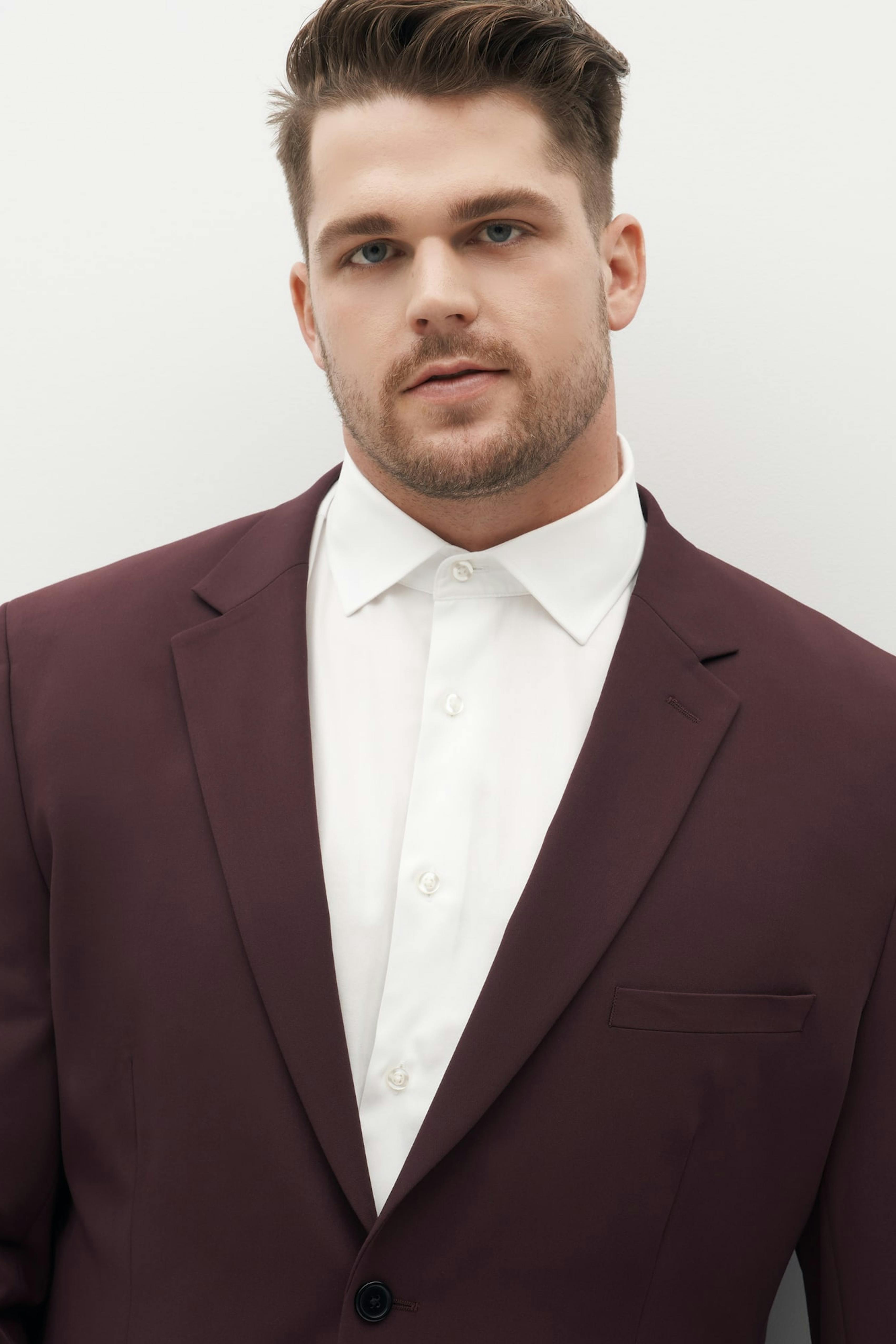 Big and tall man in a burgundy maroon suit for holiday outfit.