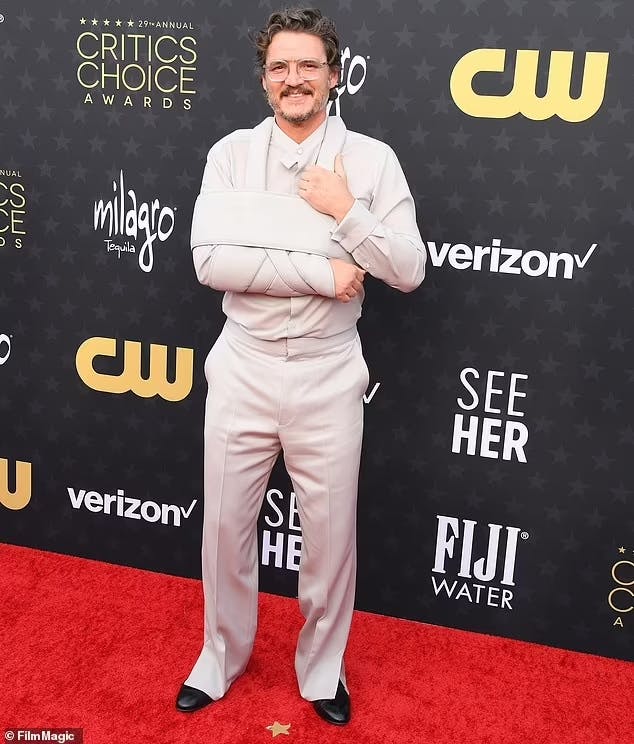 Pedro Pascal at the 2024 Critics Choice Awards in a sandy, monochrome grey beige suit and matching designer sling for his broken arm.