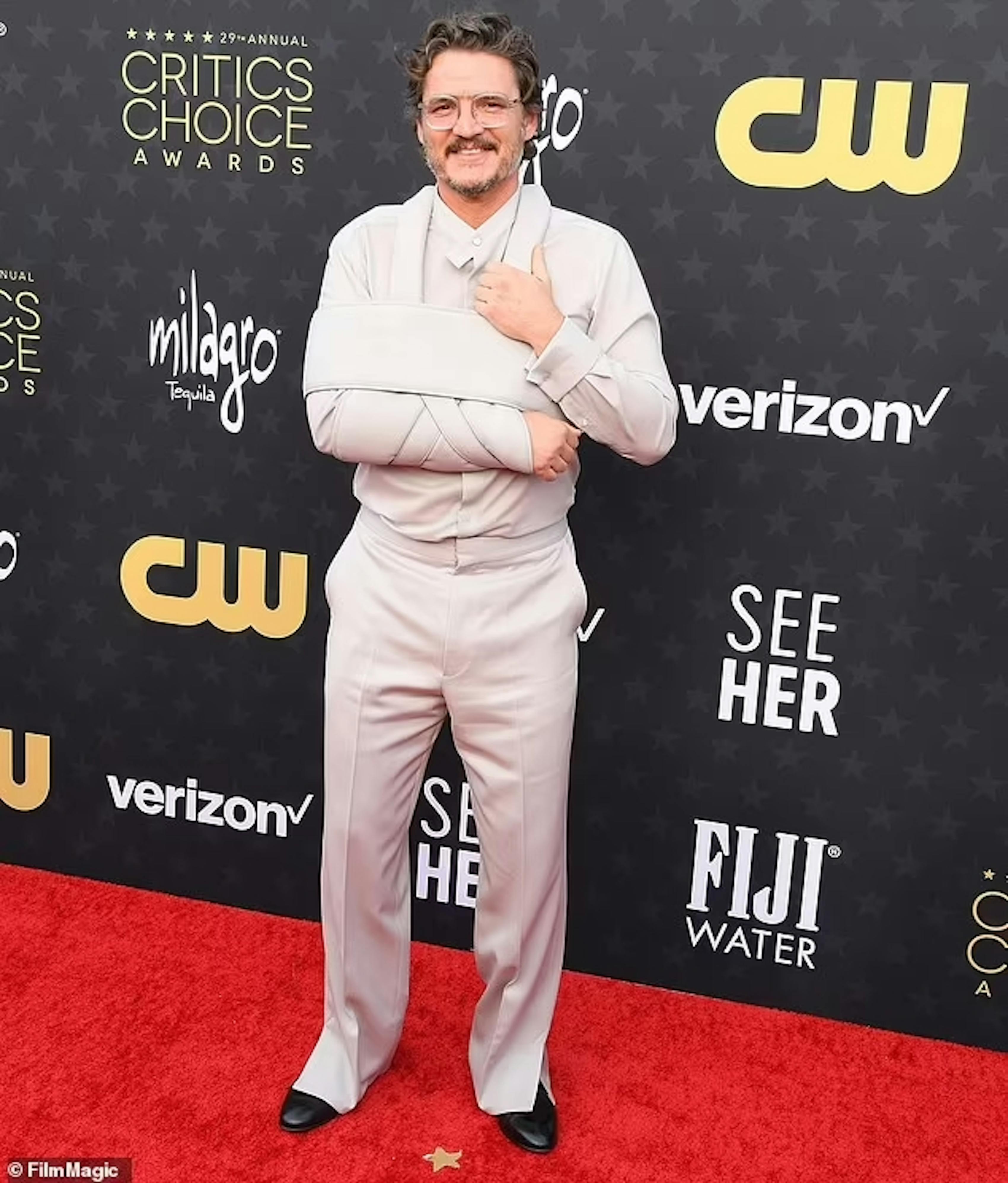 Pedro Pascal at the 2024 Critics Choice Awards in a sandy, monochrome grey beige suit and matching designer sling for his broken arm.