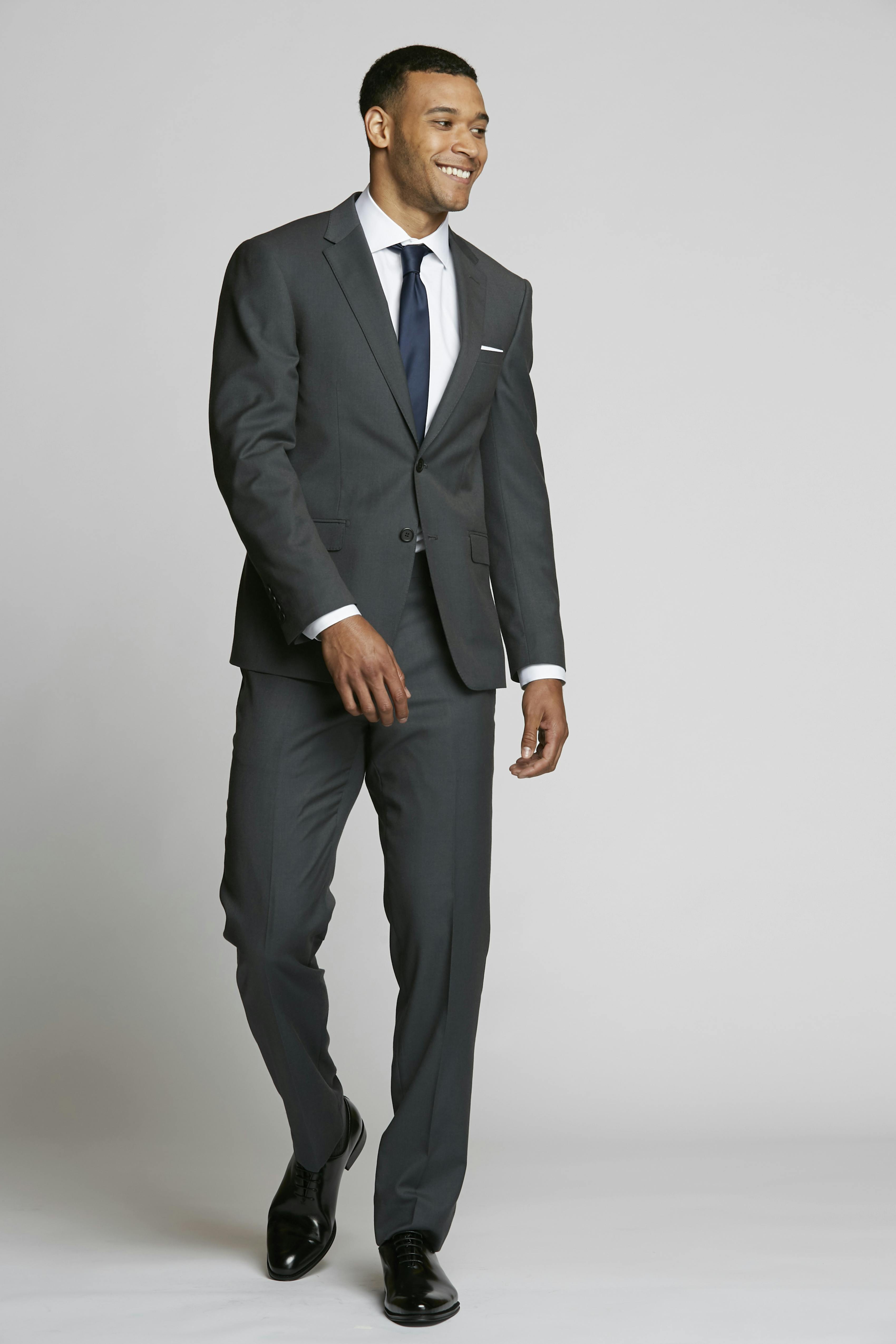 Simple, elegant charcoal grey suit outfit with a white button-up dress shirt and navy tie, perfect to wear as a guest at a formal or cocktail wedding.