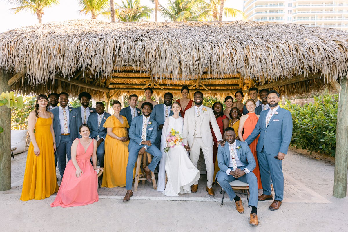 Summer and spring wedding colors with light blue groomsman suits, tan groom suit, and yellow bridesmaid dresses on the beach