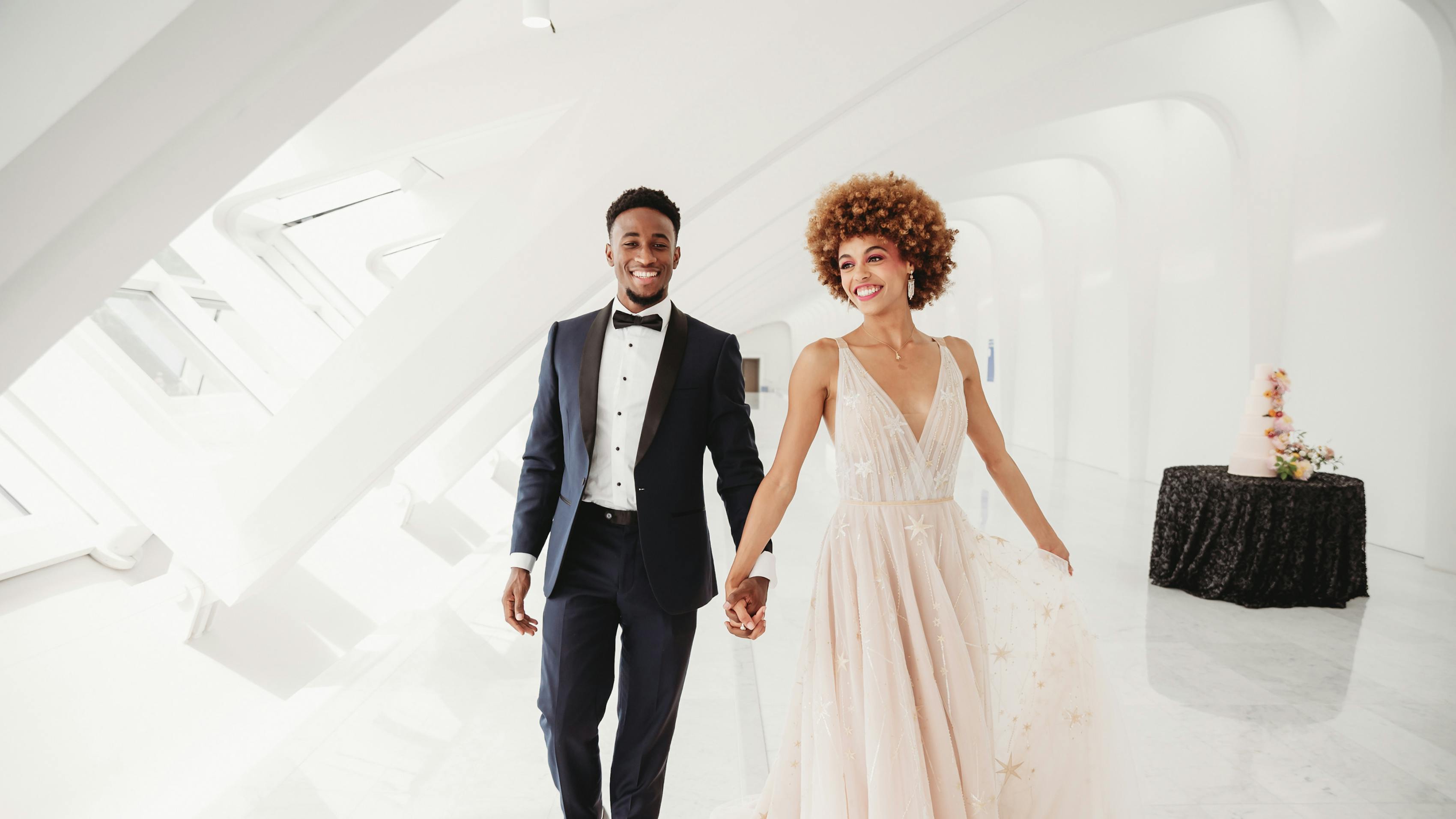 Groom wearing black tuxedo to match blush wedding dress for colorful black tie wedding