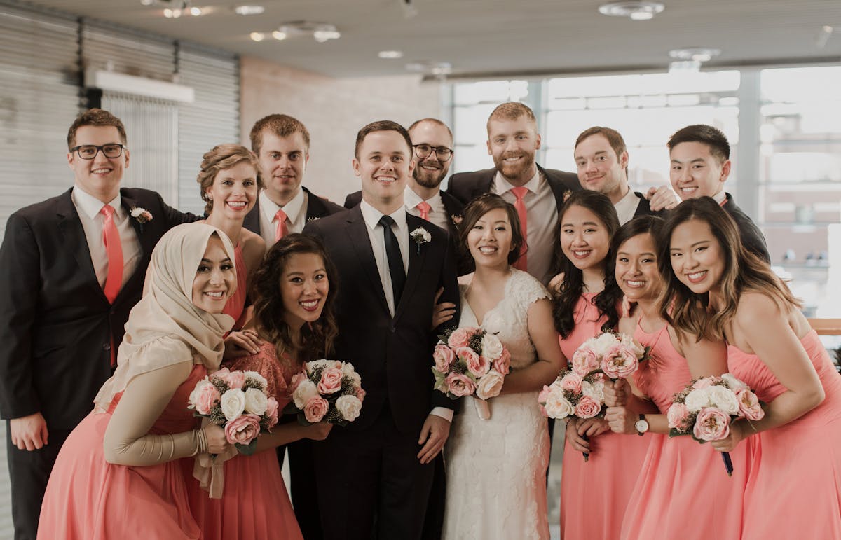 Men in black suits bridesmaids in coral dresses pantone color of the year