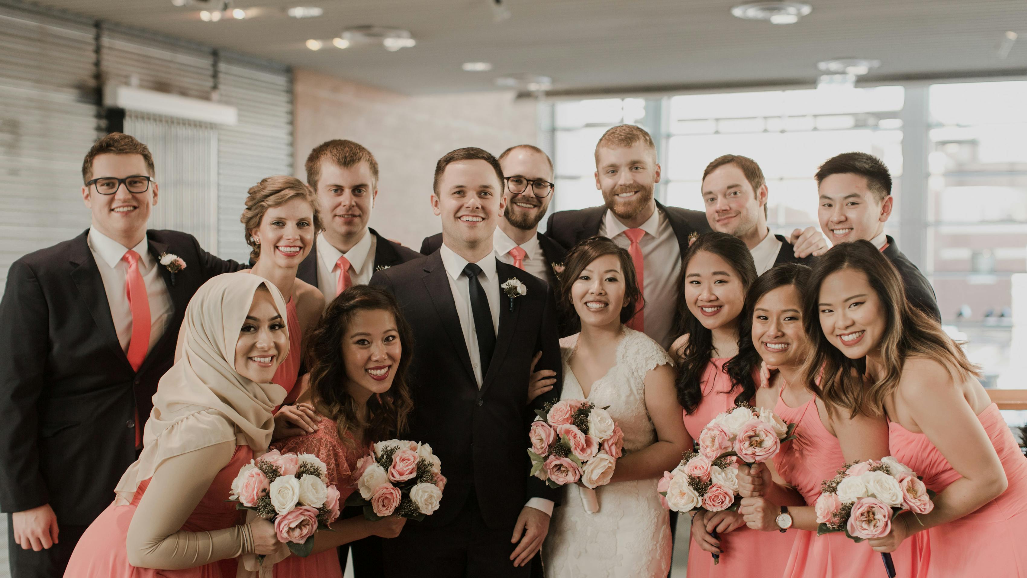 Men in black suits bridesmaids in coral dresses pantone color of the year