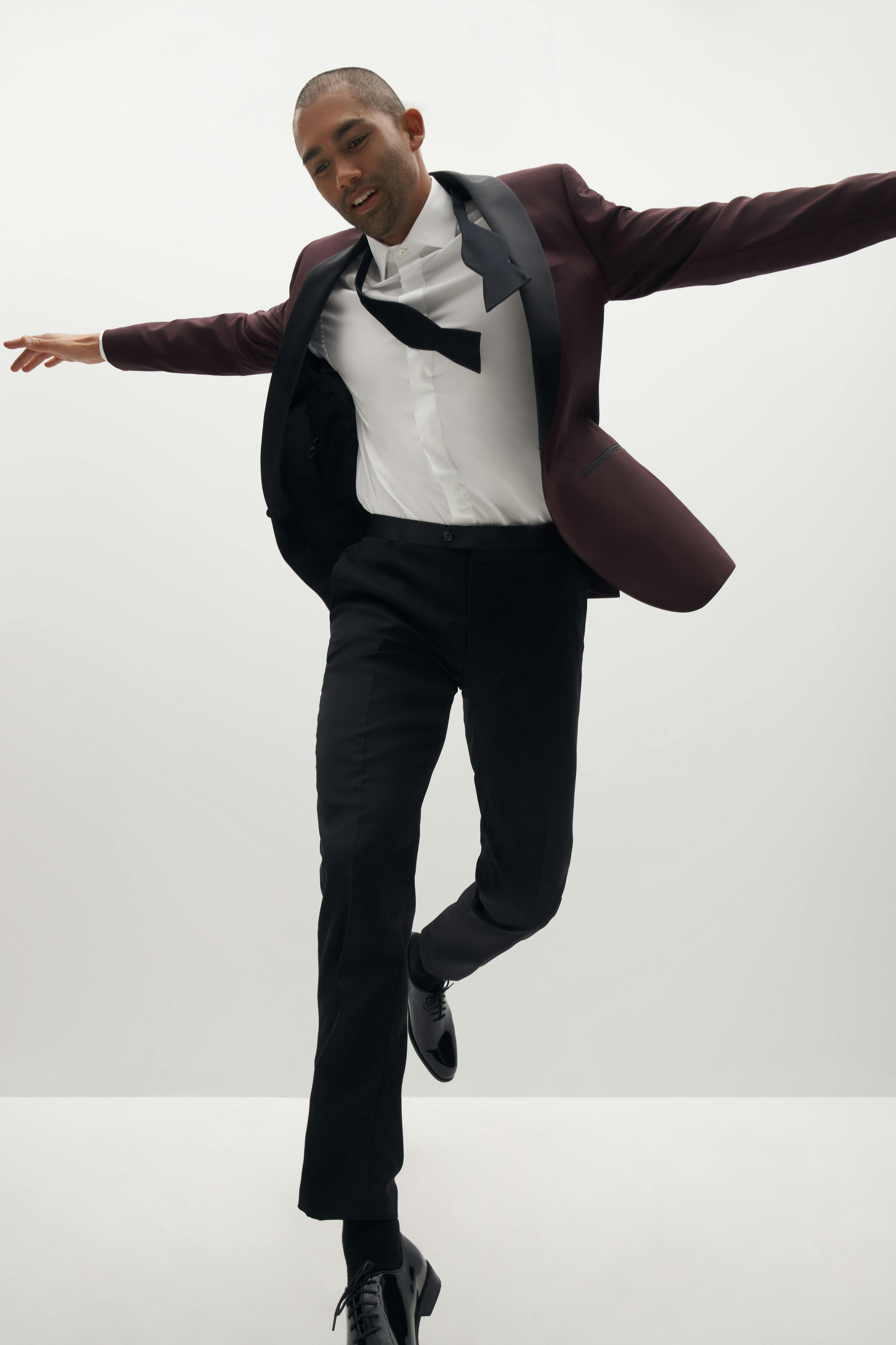 Man dancing in burgundy tuxedo with black shawl lapel.