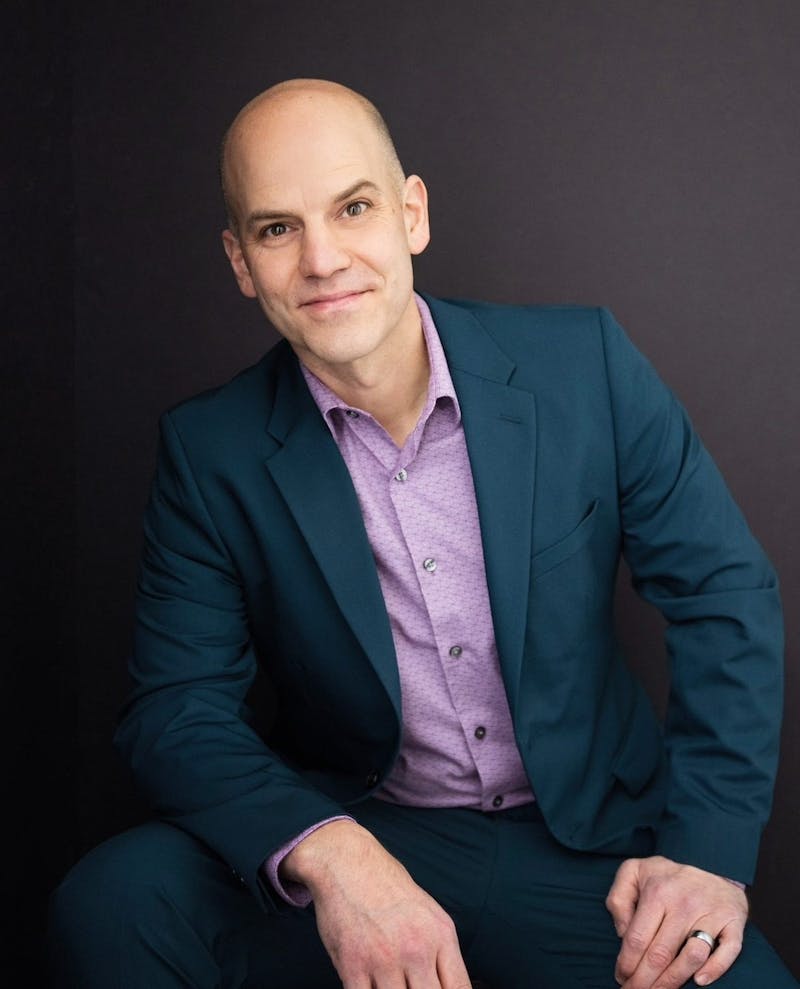 Man's professional headshot outfit wearing dark teal suit with lilac purple dress shirt.