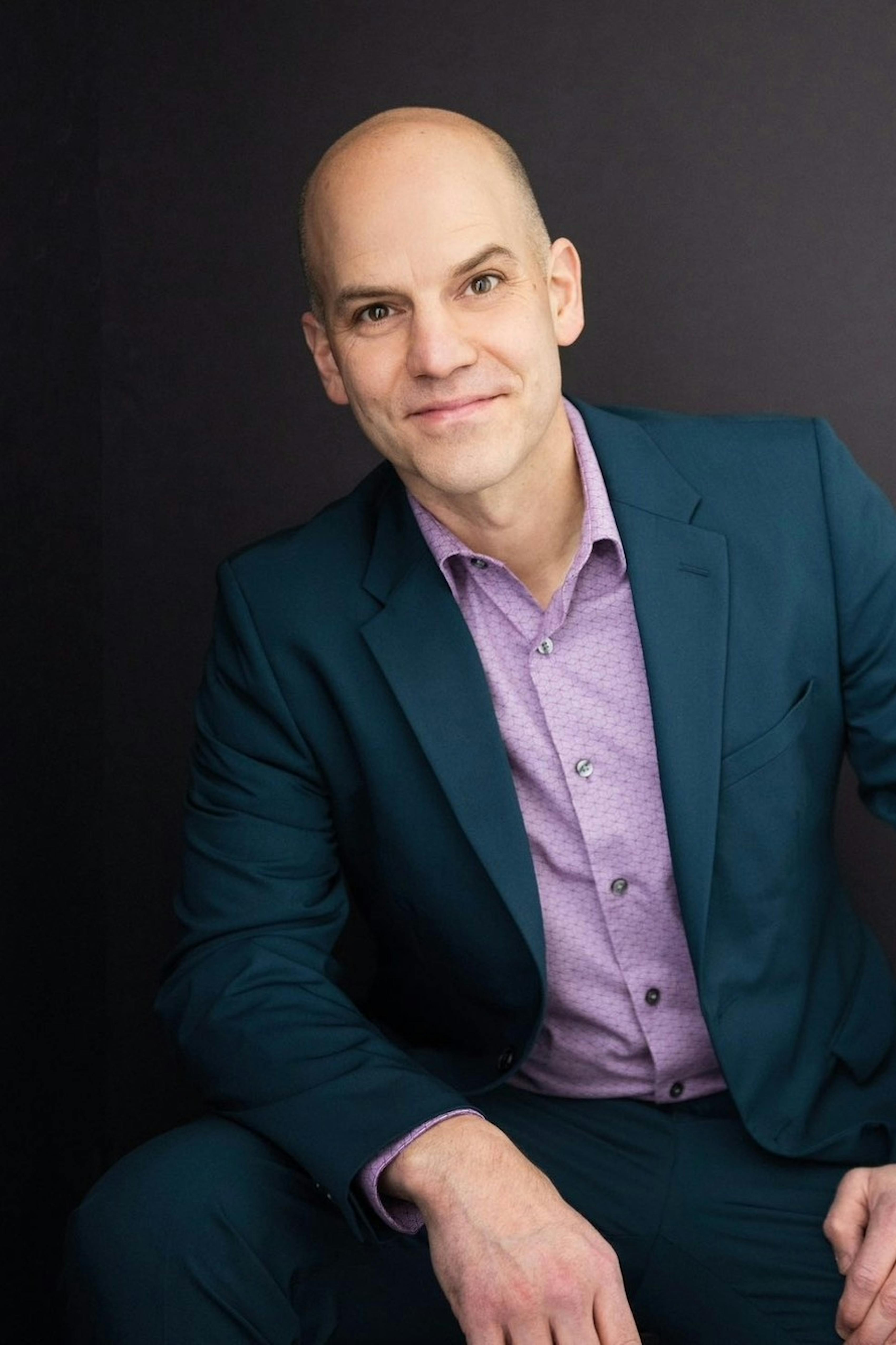 Man's professional headshot outfit wearing dark teal suit with lilac purple dress shirt.