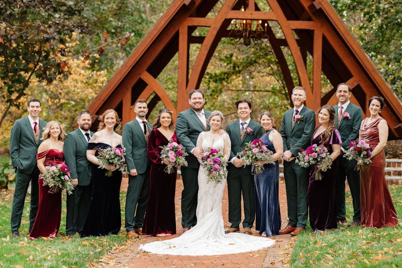 Fall colors wedding party in velvet mix and match bridesmaids dresses and forest green groomsman suits.