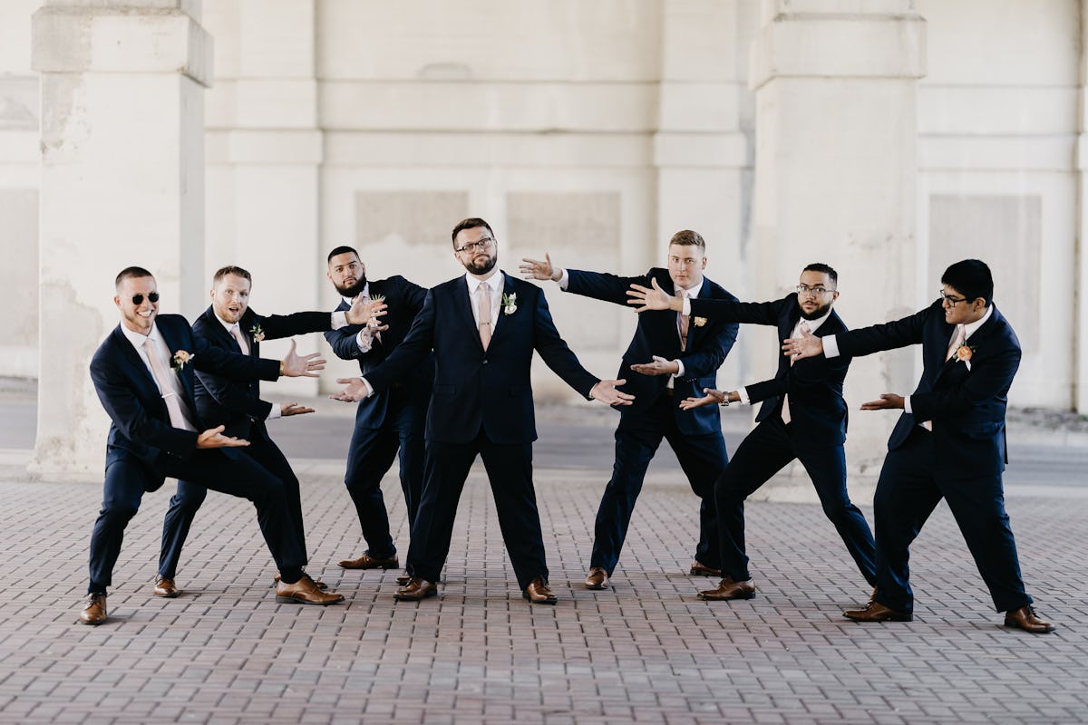 Groomsmen proud of their groom on his wedding day, wearing Navy Suits with mauve ties from Birdy Grey