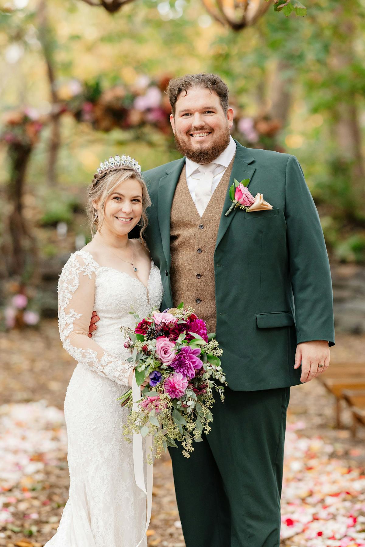Newlywed pose in front of the altar with autumn wedding vibes for bride in lace long sleeve wedding gown and groom in forest green wedding suit and tweed vest.