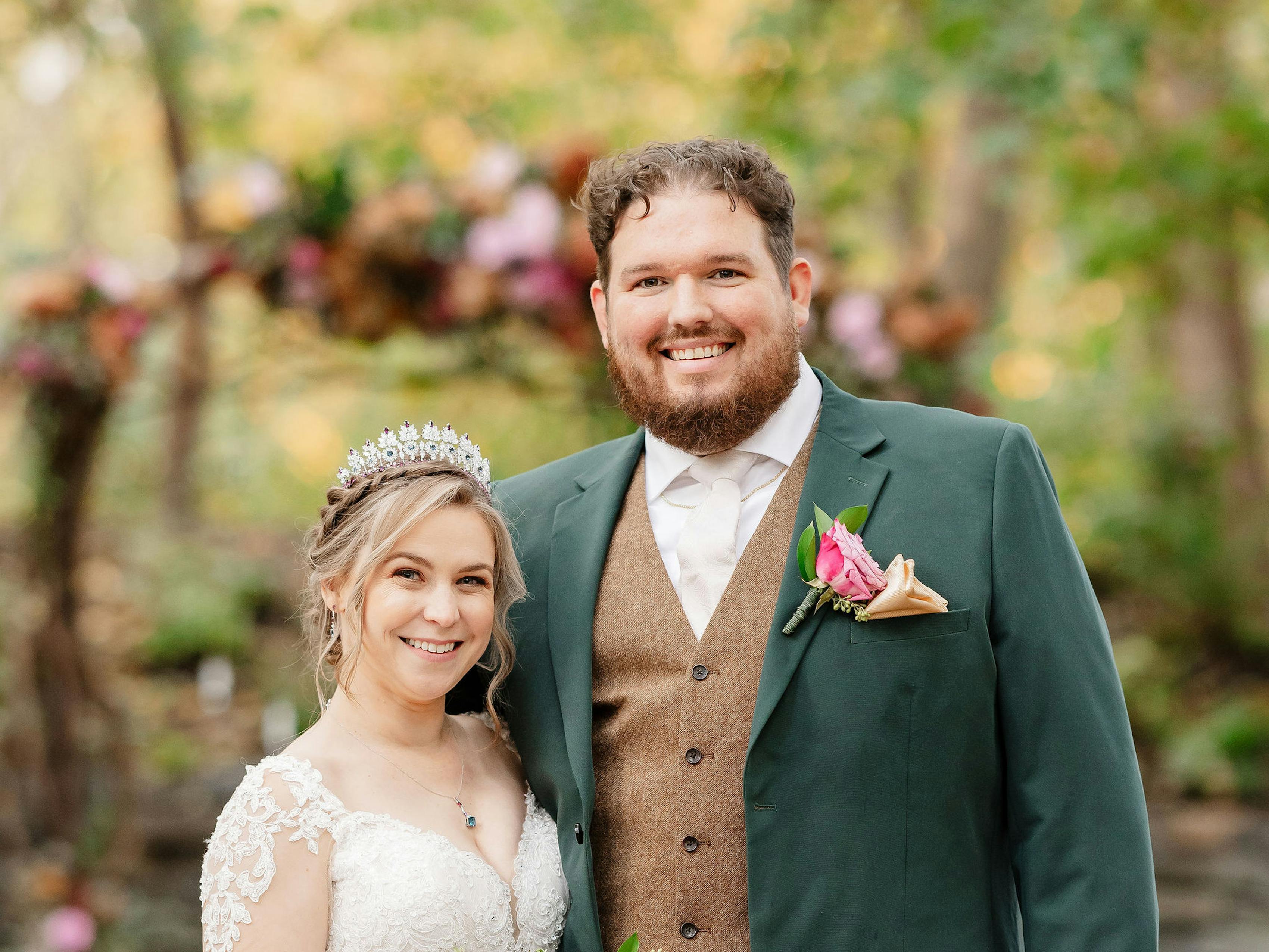 Newlywed pose in front of the altar with autumn wedding vibes for bride in lace long sleeve wedding gown and groom in forest green wedding suit and tweed vest.