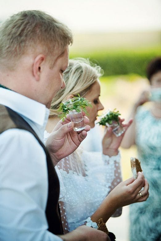 Rustic Lithuanian Wedding. Pictured: Couple practicing salt, bread, and vodka tradition. 
