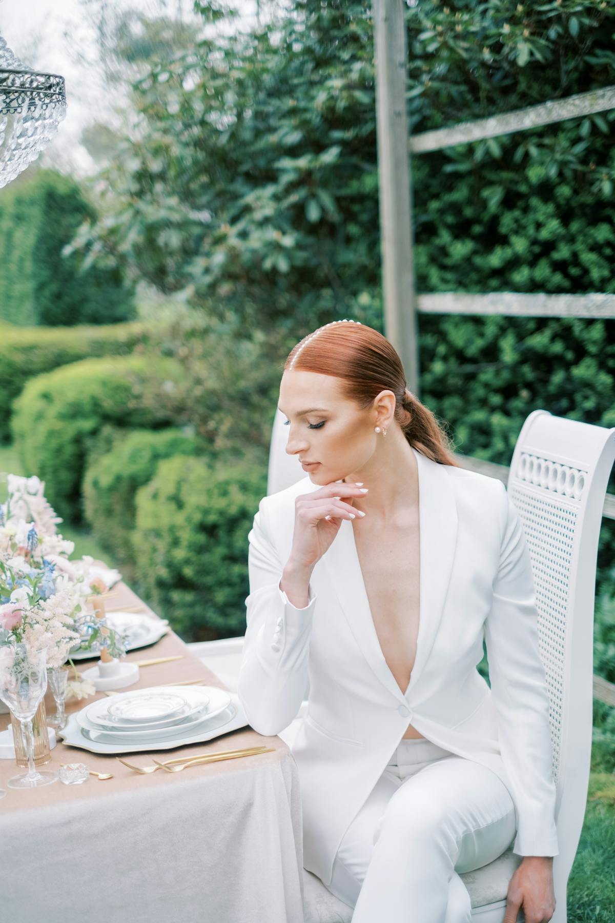 Pearlcore wedding trend with pearl hair accessories in slick bridal hairstyle wearing women's white wedding tuxedo.