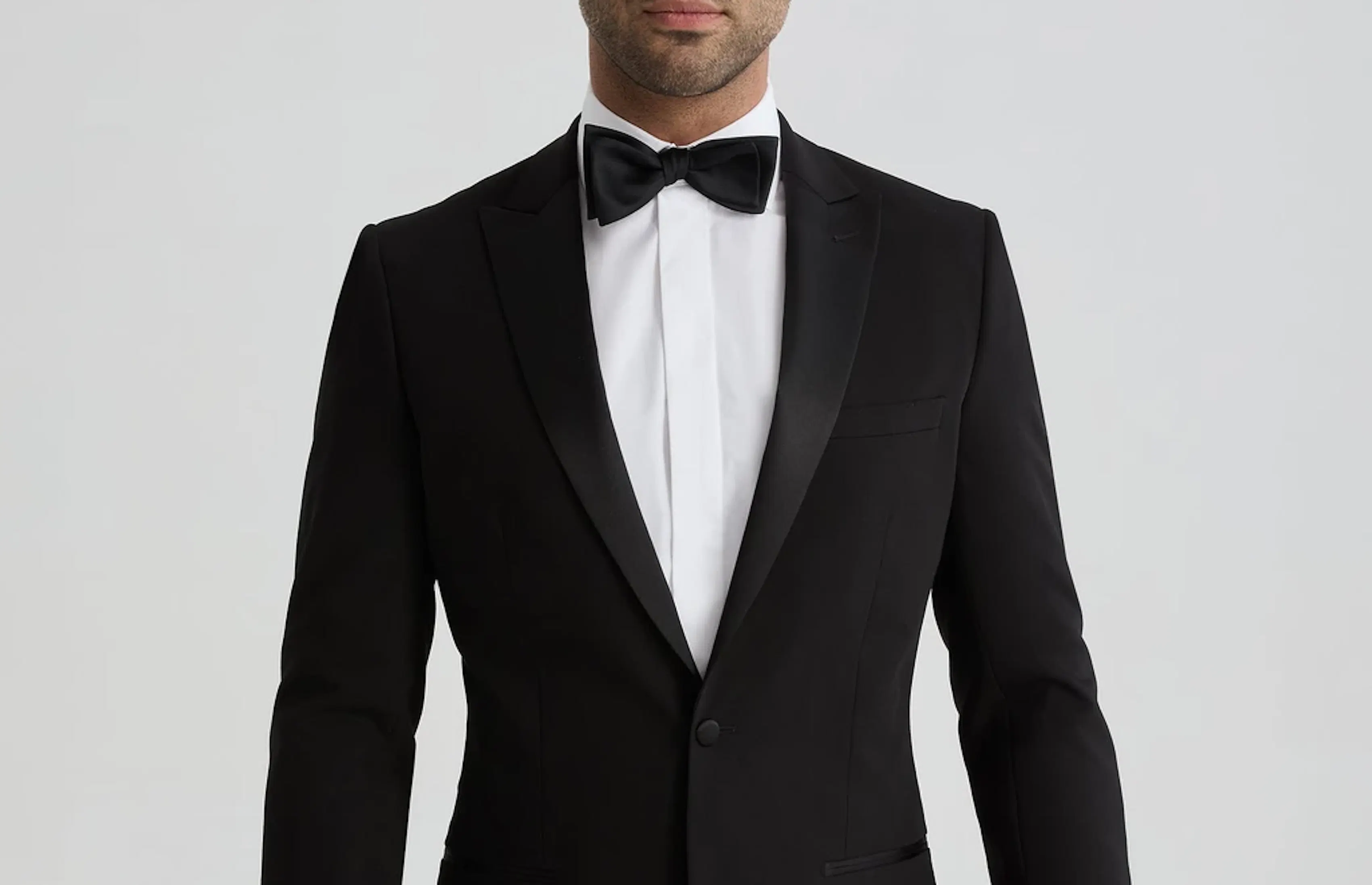 Black peak lapel tuxedo with black bow tie and white dress shirt for a formal wedding or event.