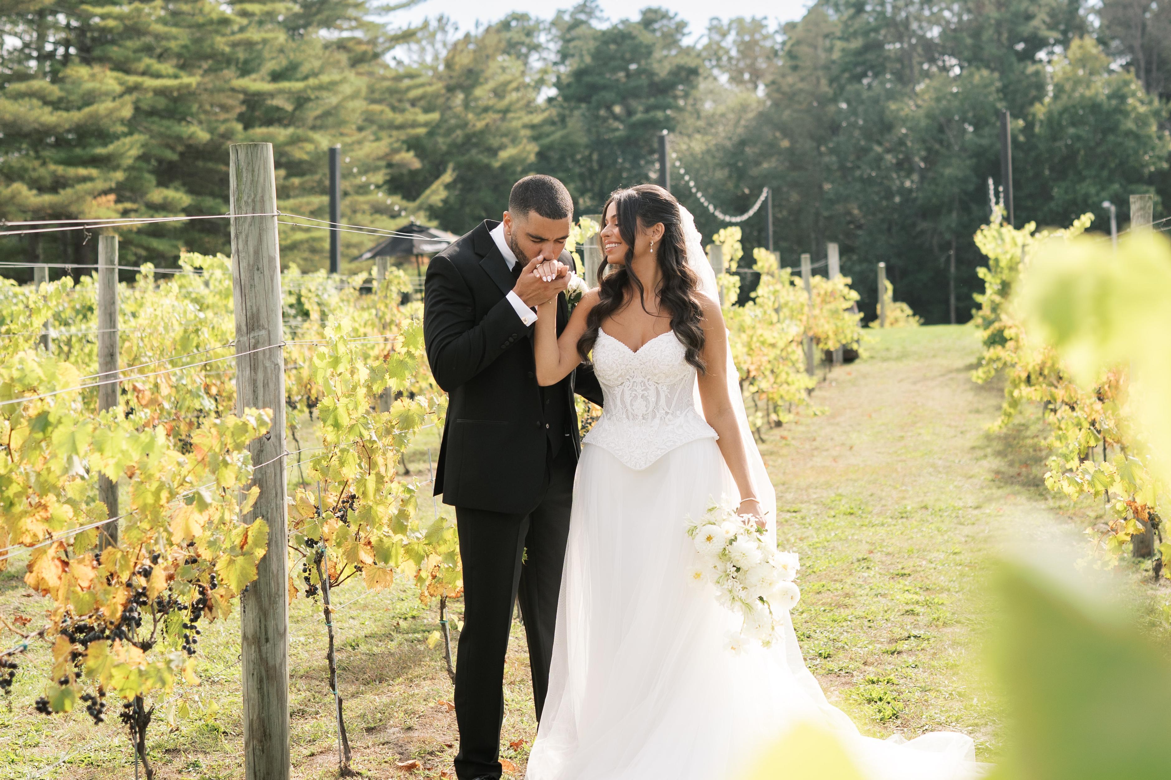 Bride and groom sharing a romantic moment during a vineyard wedding ceremony surrounded by grapevines and greenery