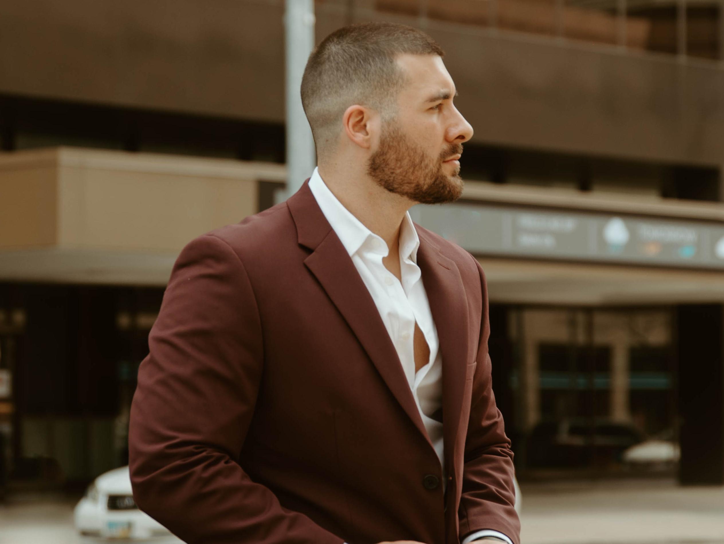 Man wearing a burgundy suit with an open-collar white shirt for a fall wedding look.