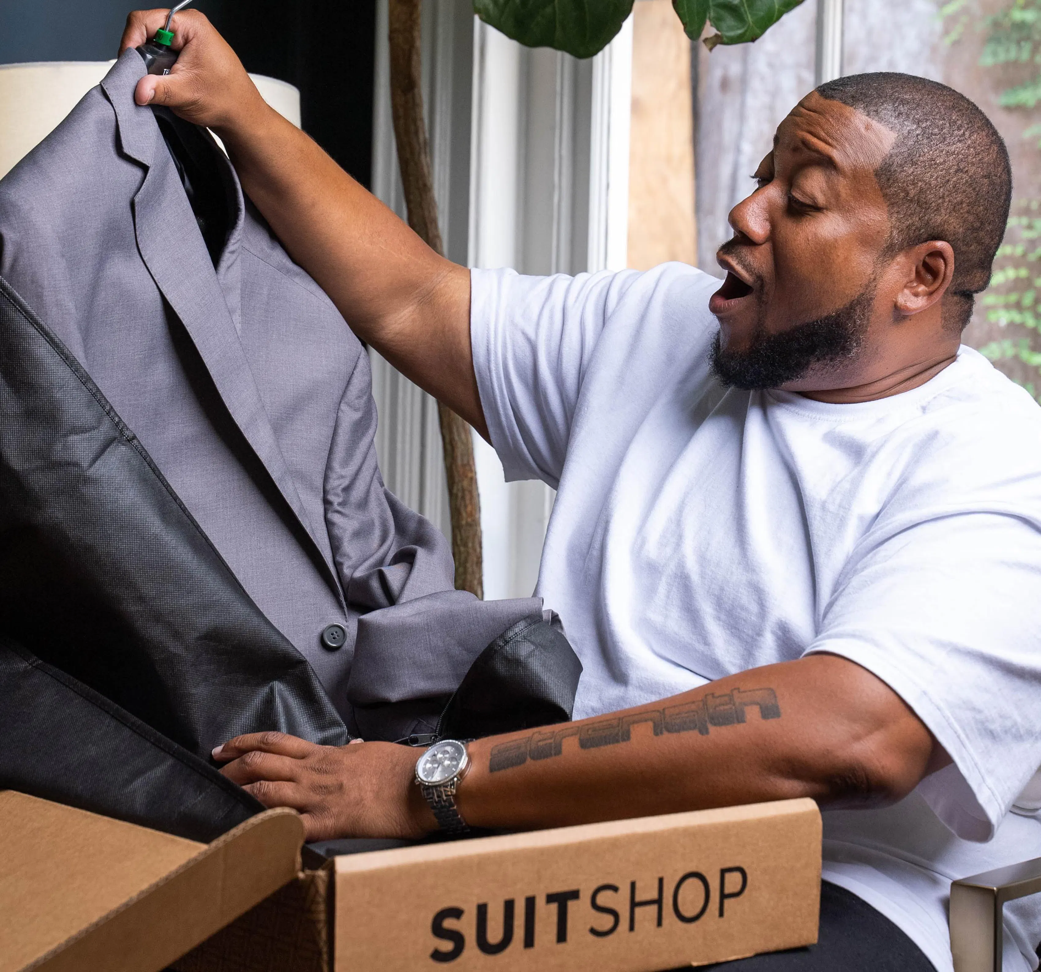 Man opening a SUITSHOP package with a gray suit jacket for a big and tall suit fit.