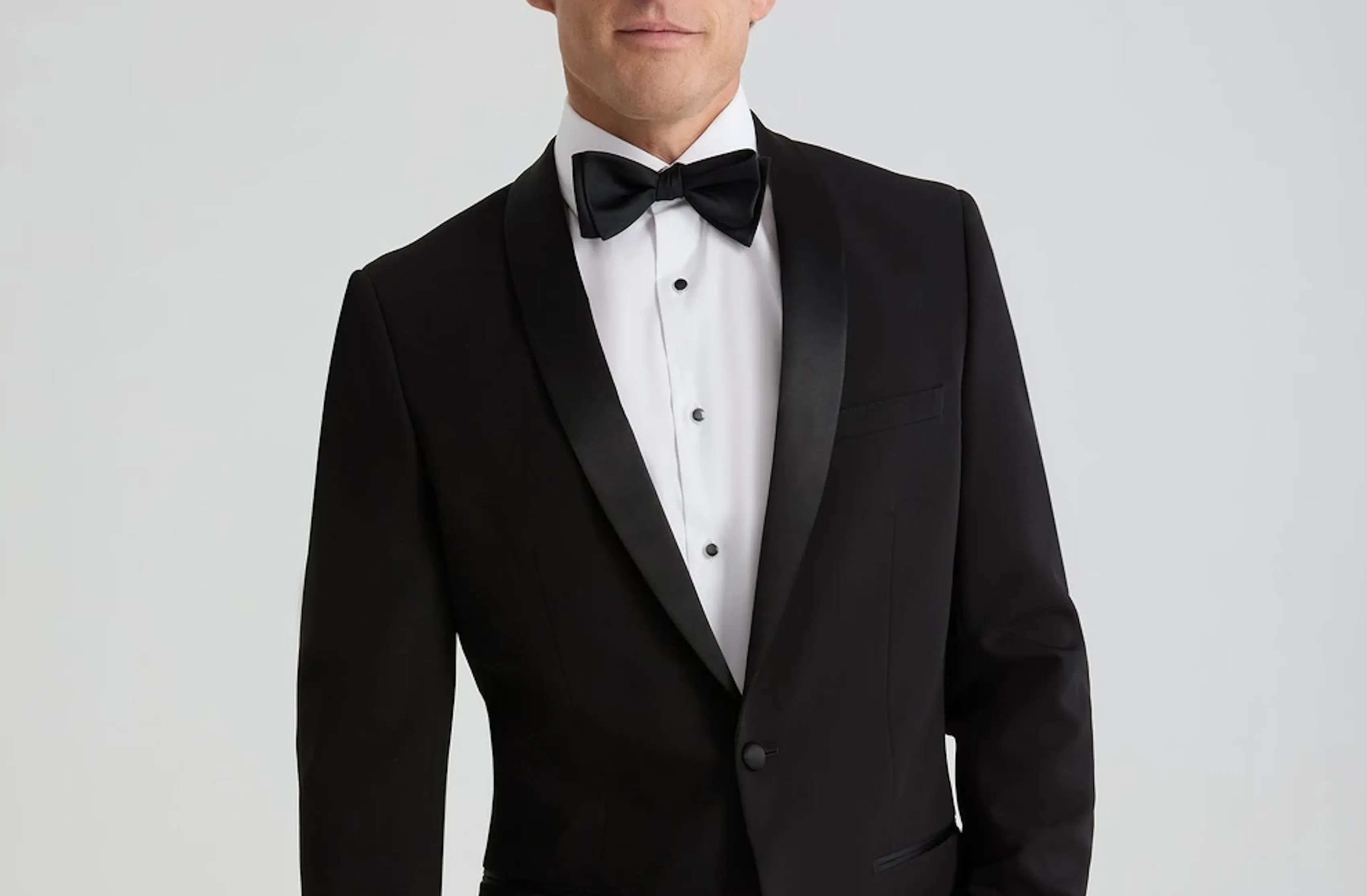 Black shawl lapel tuxedo with black bow tie and white dress shirt for a formal wedding or event.